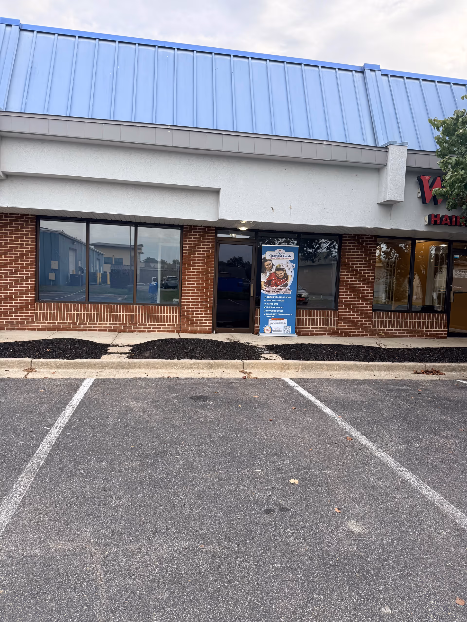 Exterior view of Cherished Hands Home Healthcare building with brick walls and a blue roof.