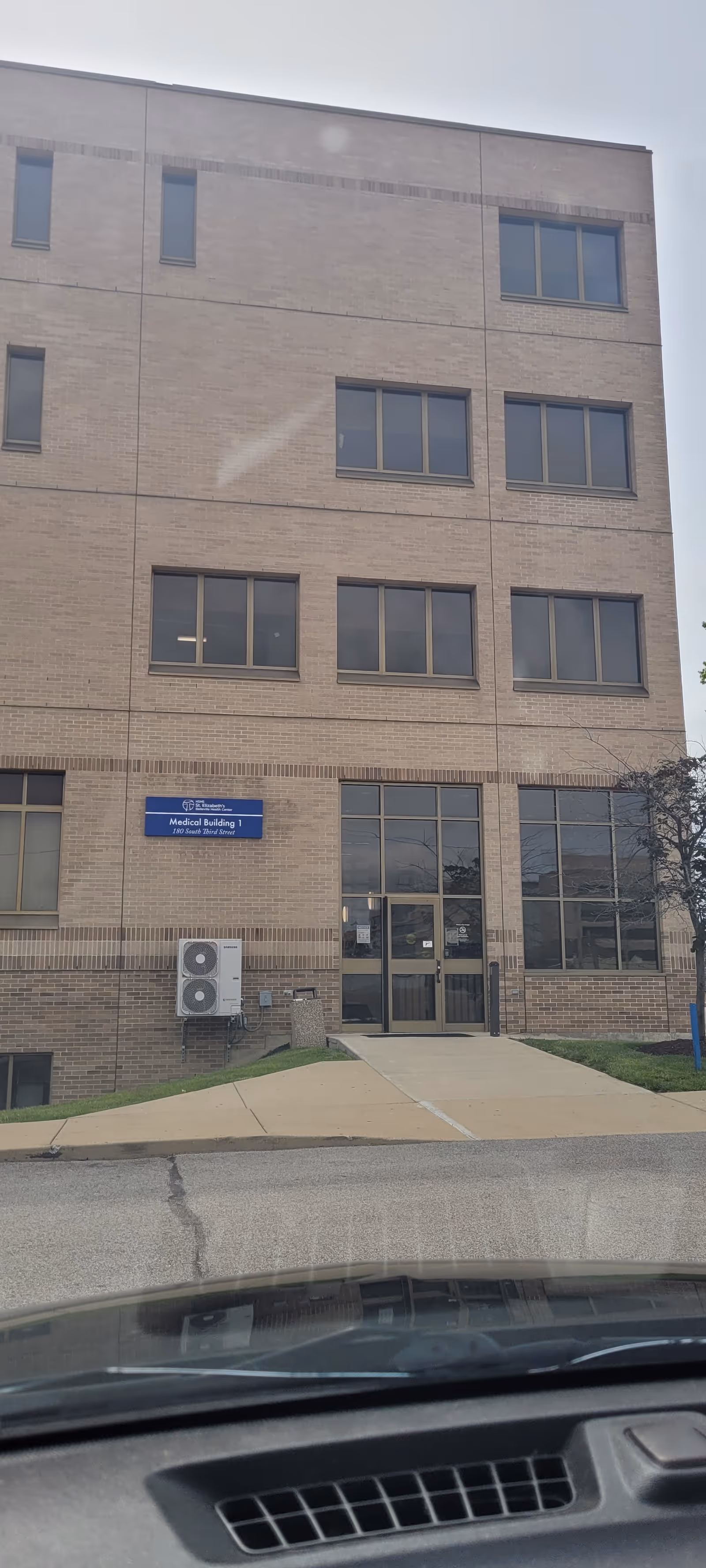 Brick, multi-story medical building exterior with glass entrance and an outside A/C unit.