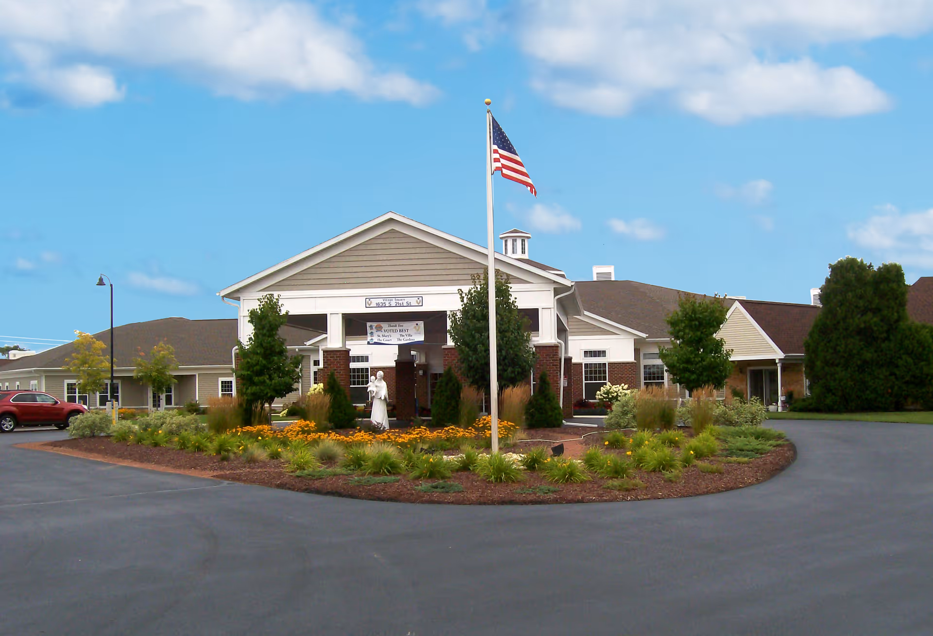 Front exterior of St Marys Home for the Aged with flagpole and landscaped circular driveway.