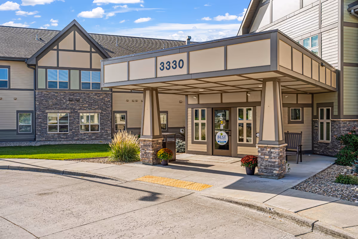Exterior view of Prairie Pointe Assisted Living entrance with covered drop off and landscaping