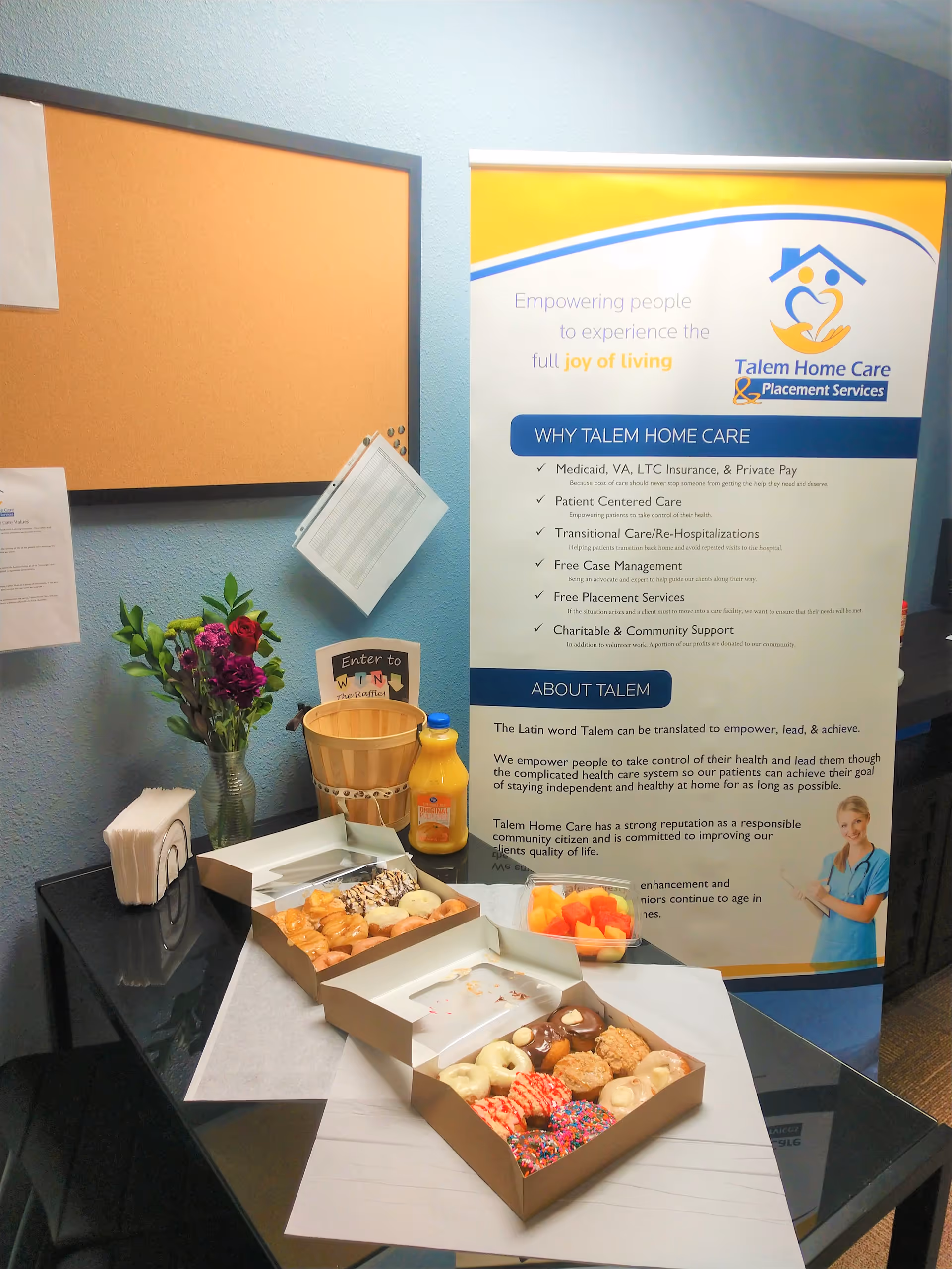 Table with donuts, juice, flowers, and a Talem banner in a lobby area.