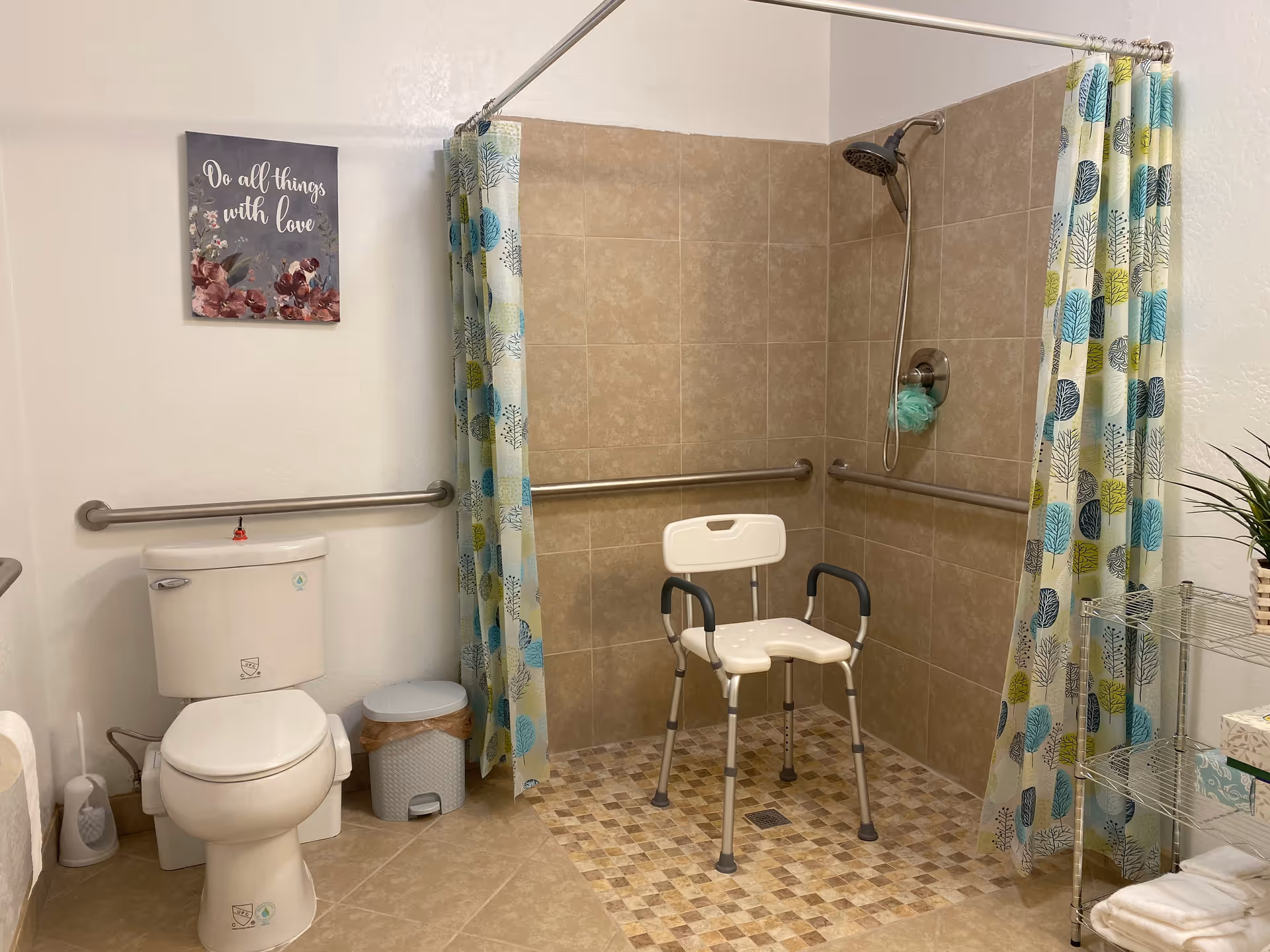 Accessible bathroom featuring a shower stall with a shower chair and grab bars, a toilet, and patterned shower curtains.