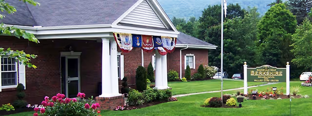Brick facility with white columns, patriotic bunting, and a Berkshire Health Care Center sign.
