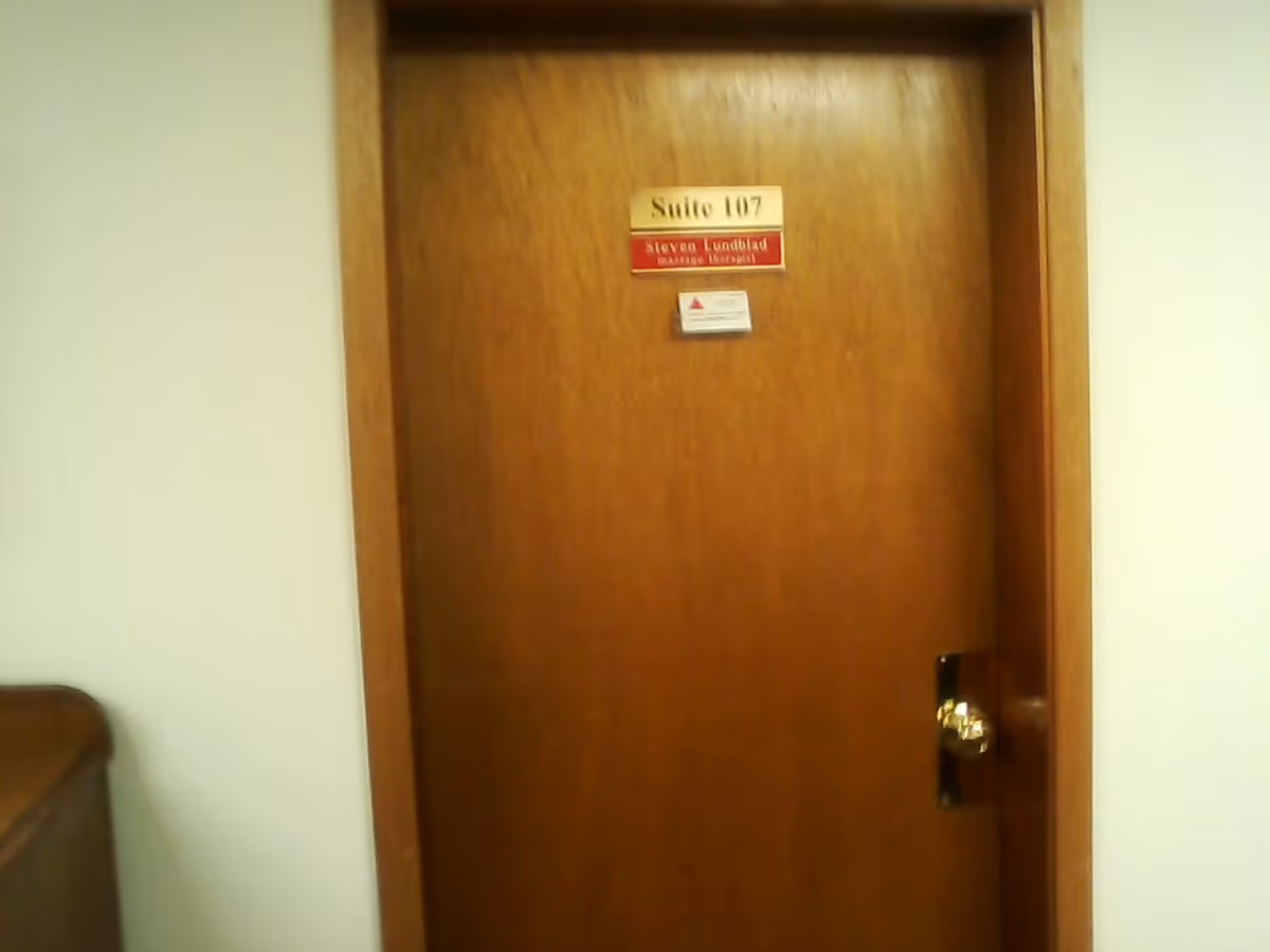 Wooden door labeled Suite 107 in a neutral facility hallway.