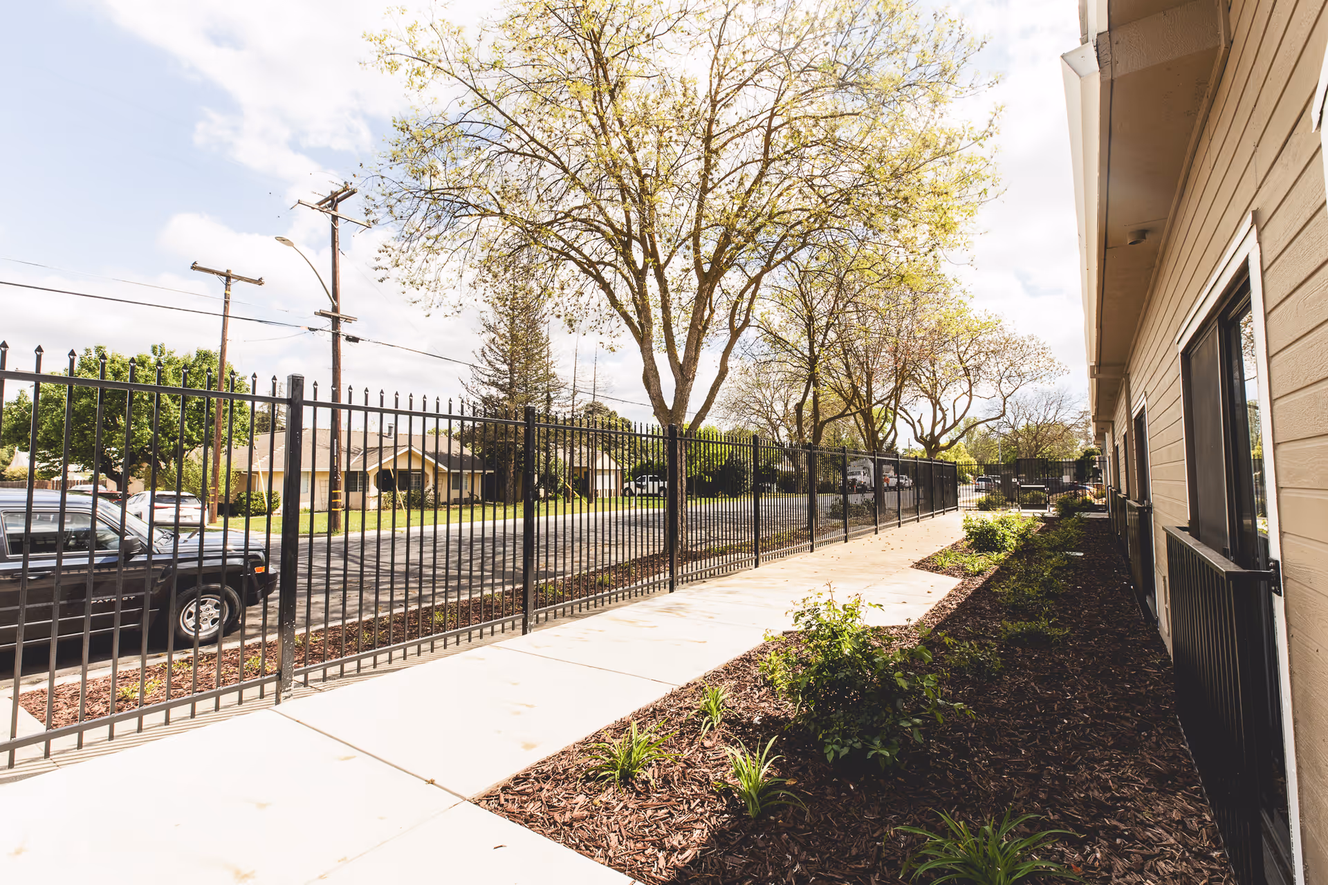 Sunny exterior view of a Morningstar Assisted Living building with a black metal fence.