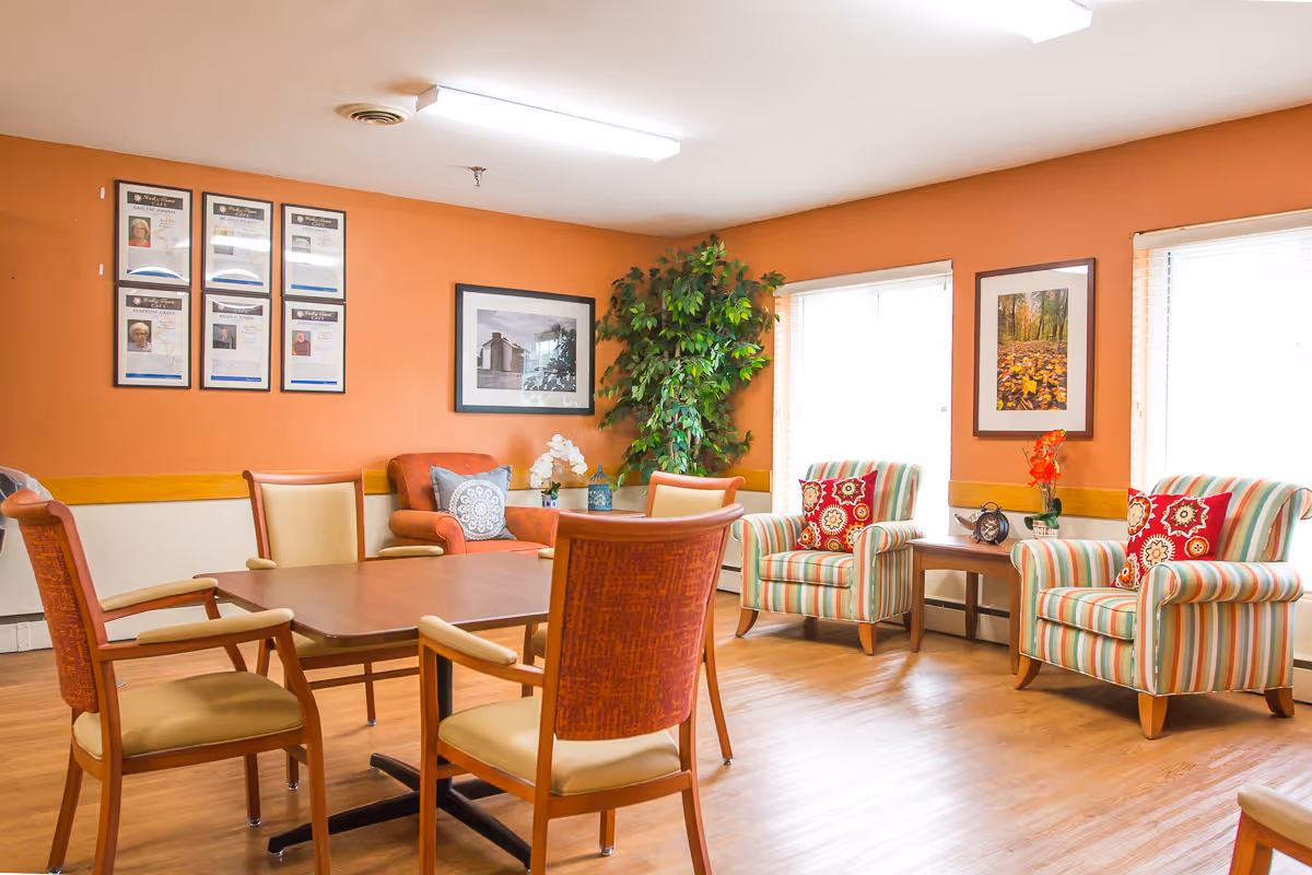 A communal dining and sitting area with a large table, upholstered chairs, and wall art.