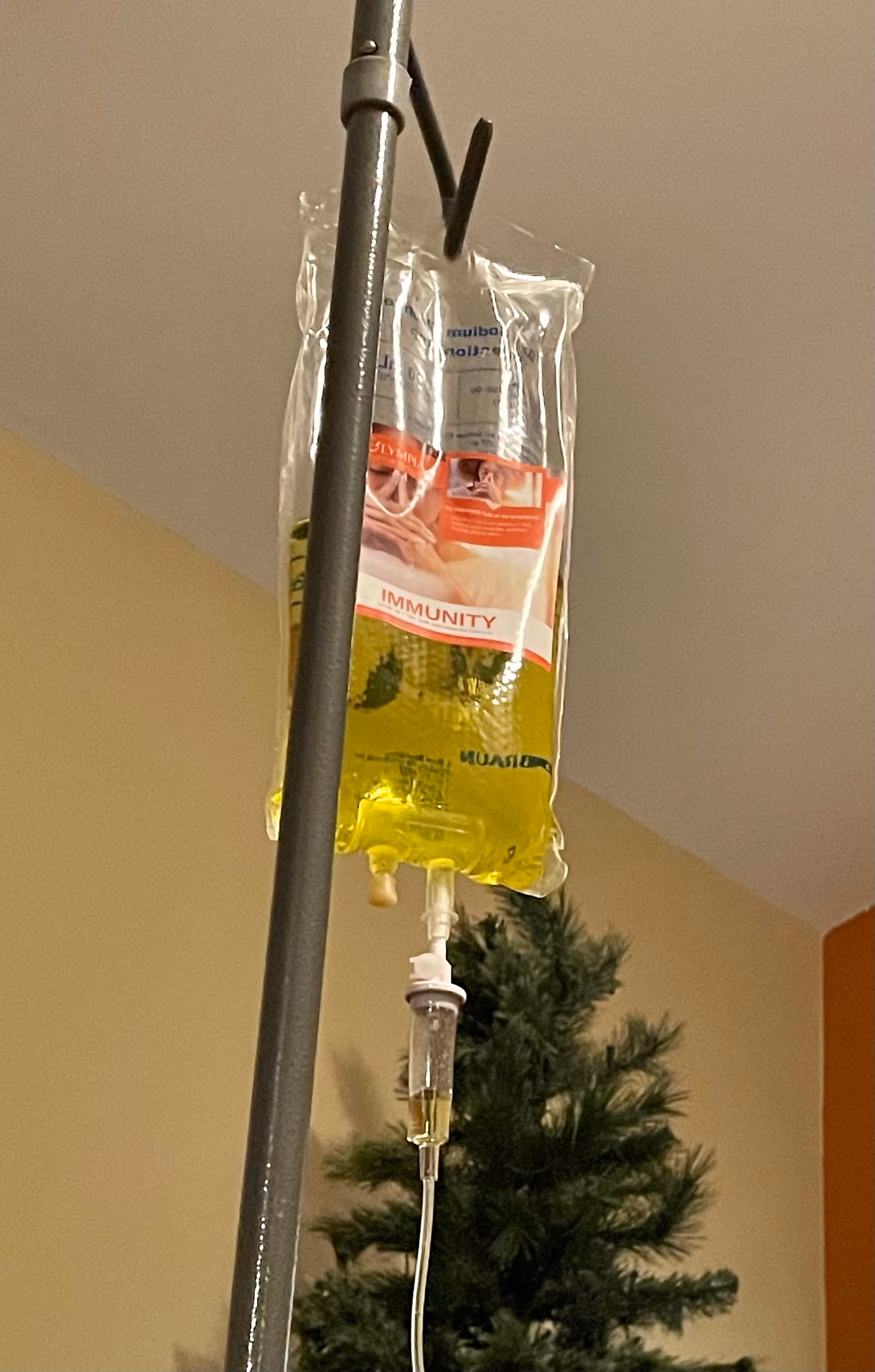 IV bag with yellow liquid hangs from a pole inside a clinical room.