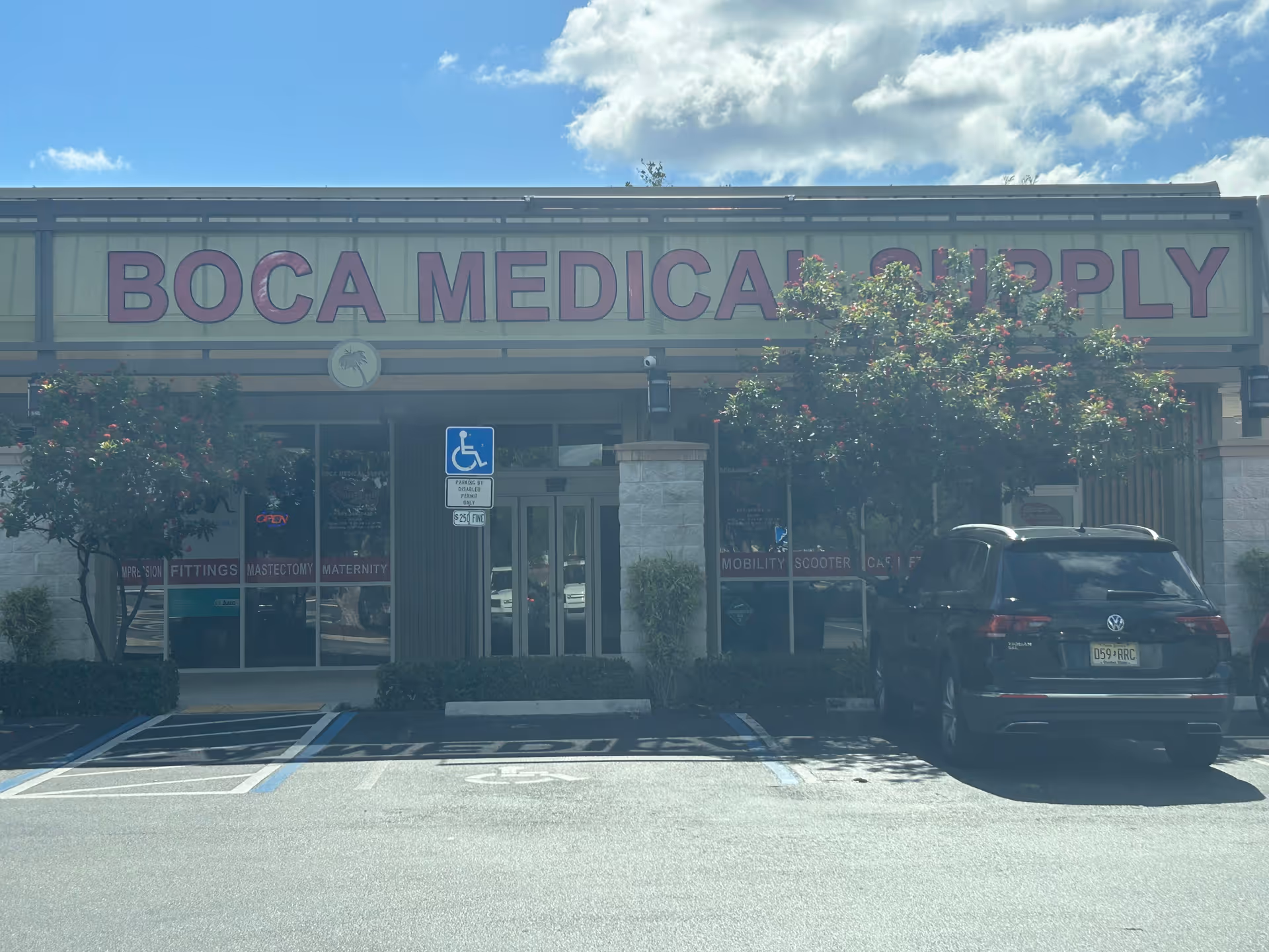 Storefront of Boca Medical Supply with parking lot, handicap sign, and trees.