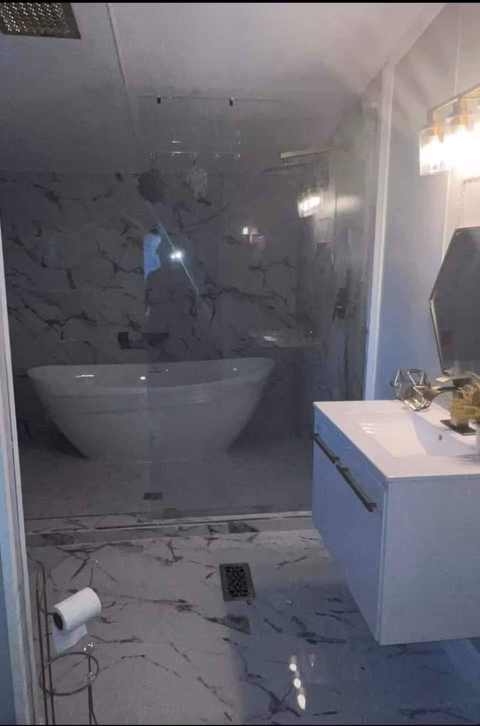 Luxurious marble bathroom with glass shower, freestanding tub, and white vanity.