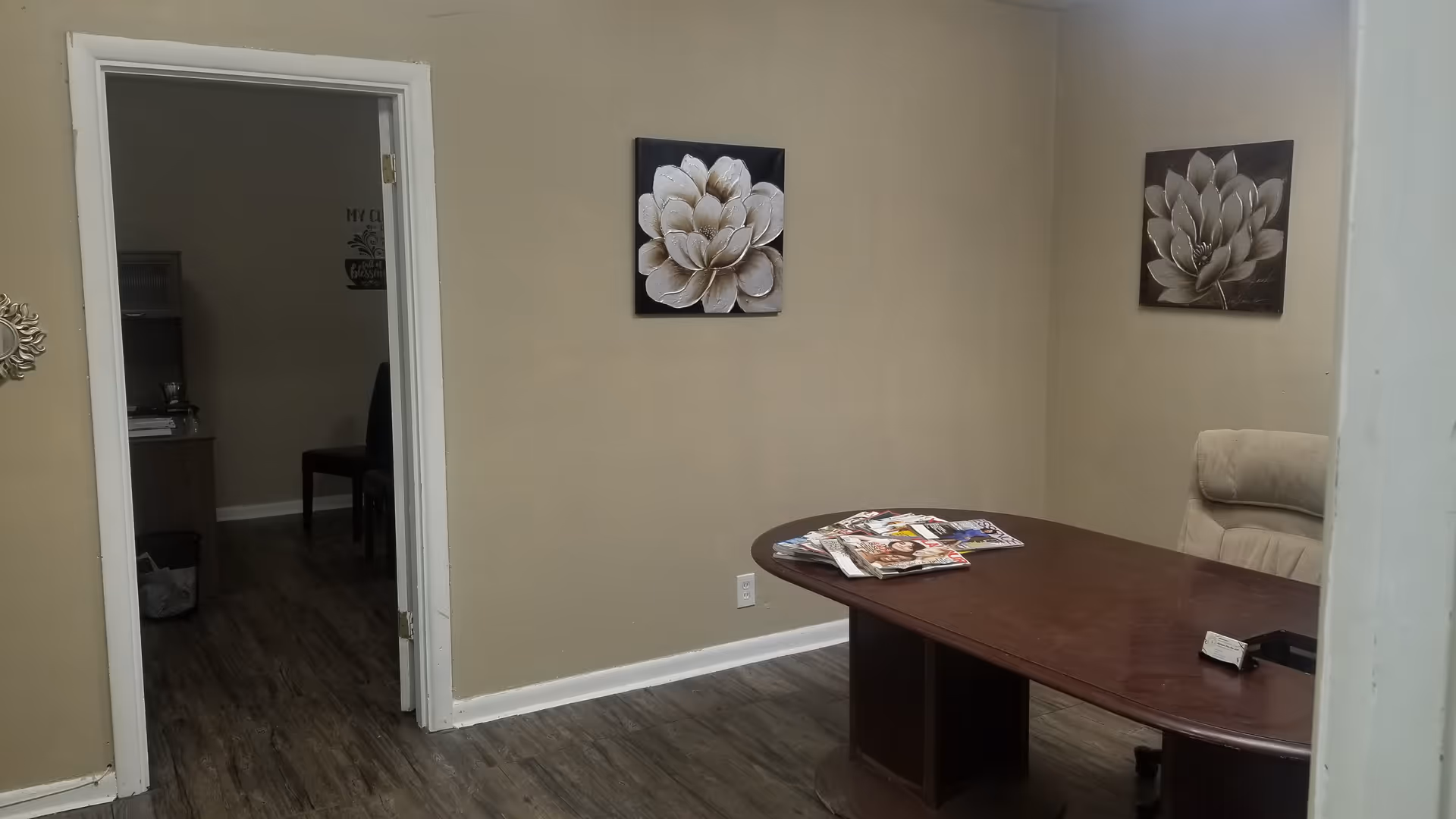 Office-like room with a curved wooden desk, magazines, and wall art.