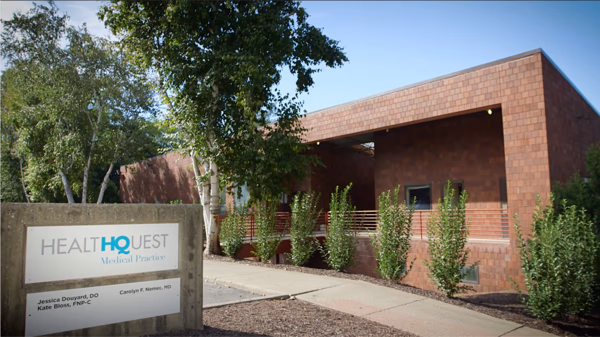 Exterior view of a red brick building with a HealthQuest sign and trees nearby
