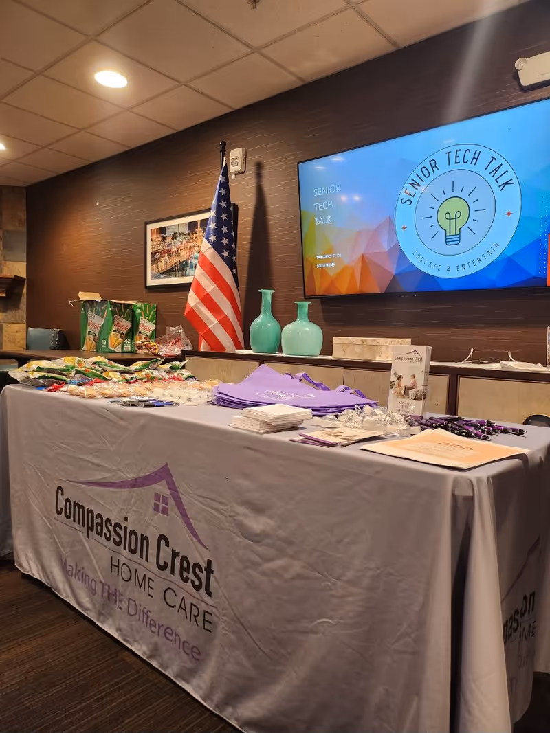 Indoor lobby area with a Compassion Crest table, American flag, and presentation screen.