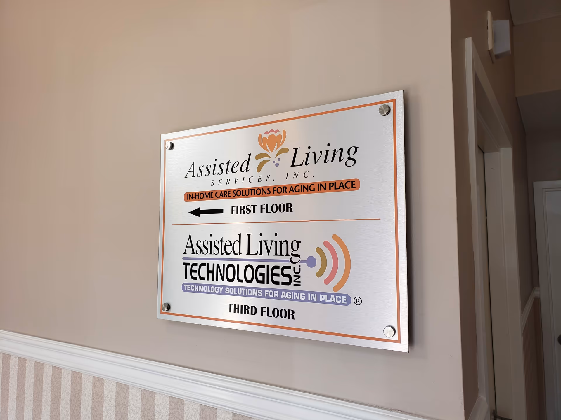 Interior wall with a double-sign plaque for Assisted Living services on first and third floors.