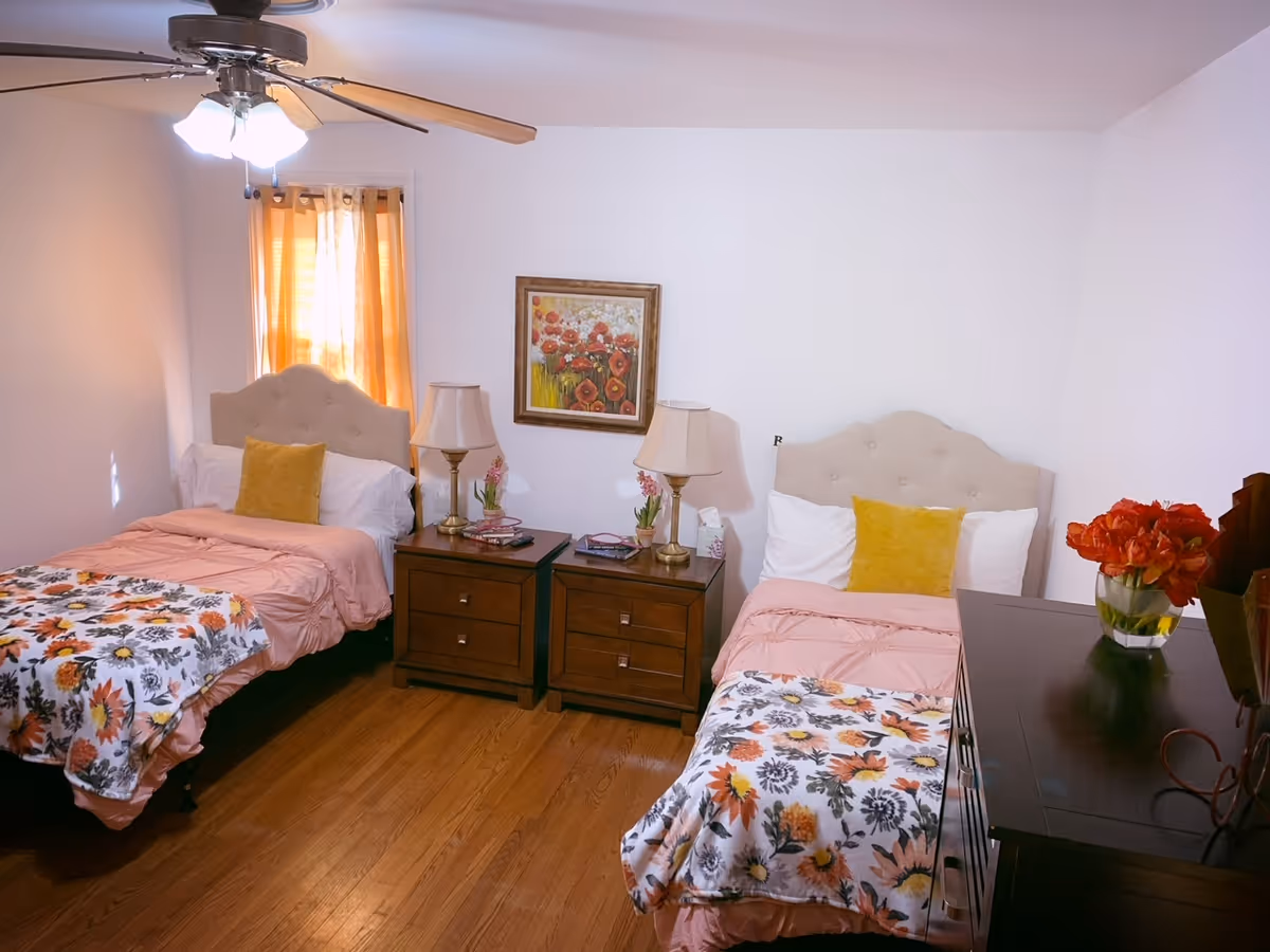 Two twin beds with nightstands and lamps in a bright, cozy floral-patterned bedroom.