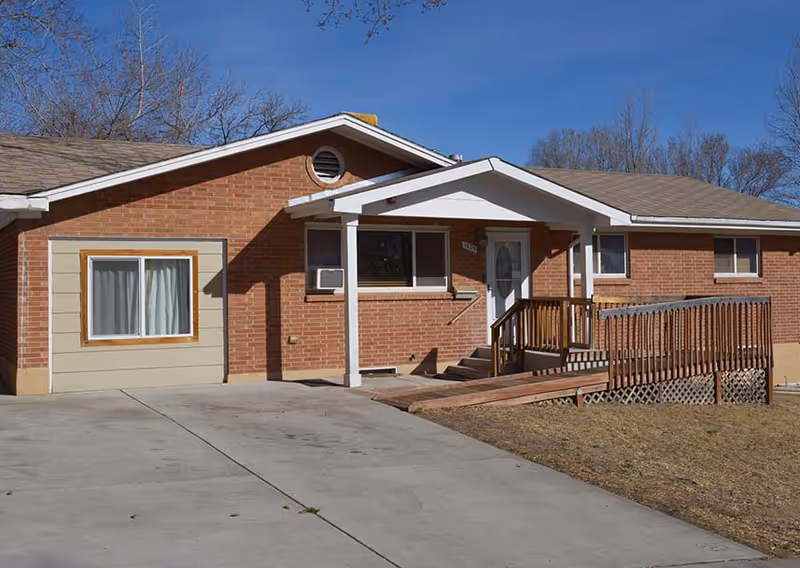 Exterior view of a single-story brick assisted living facility with a ramped entrance.