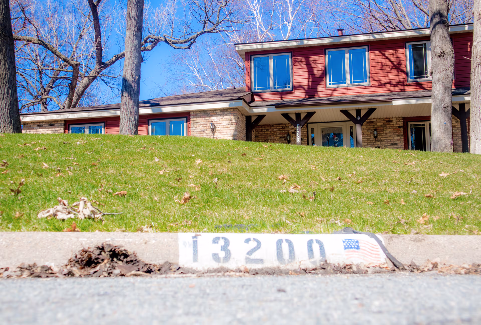 Exterior view of a red-brick senior living building with a green lawn and numbered curb.