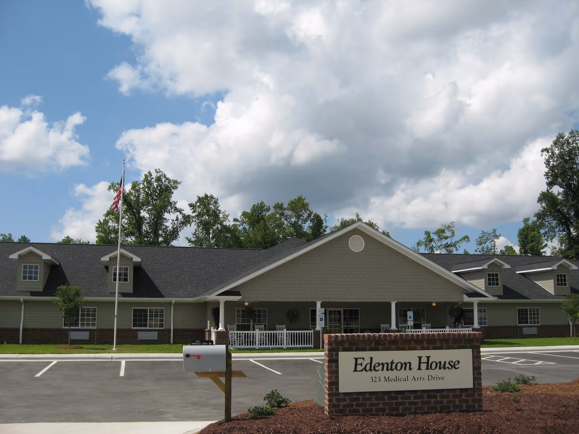 Exterior view of Edenton House senior living facility with sign and parking.