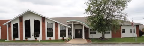 The Timbers Assisted Living building exterior with entrance canopy and surrounding lawn