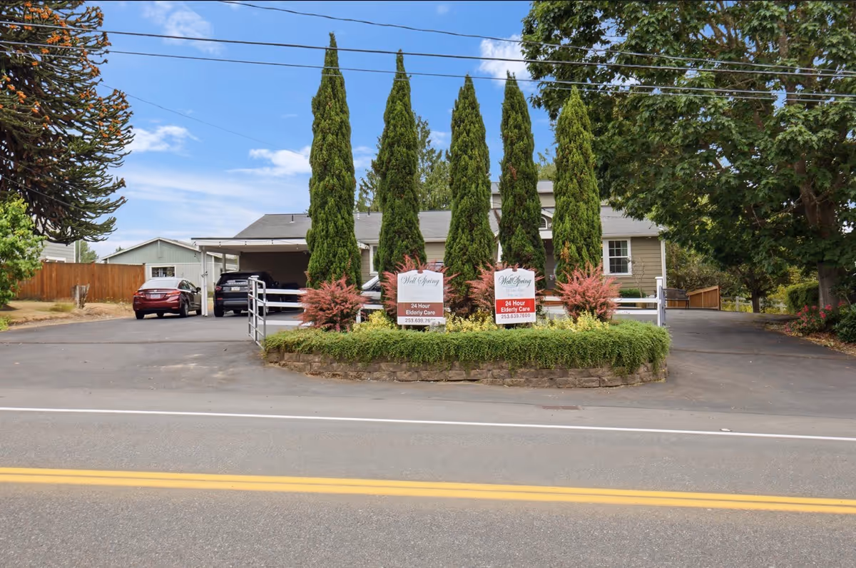 Wellspring 24 HR Elderly Care building with a landscaped median and parking in front.