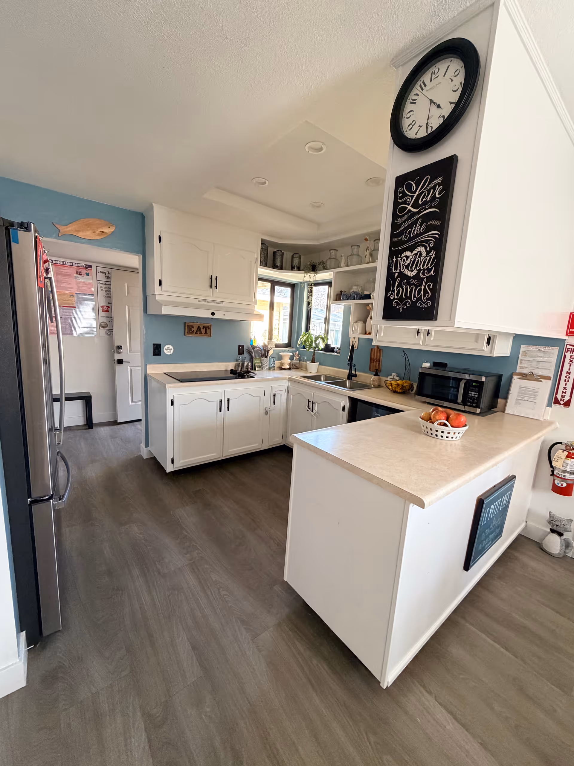 Bright kitchen in a senior living facility with white cabinets, blue walls, and a central island.