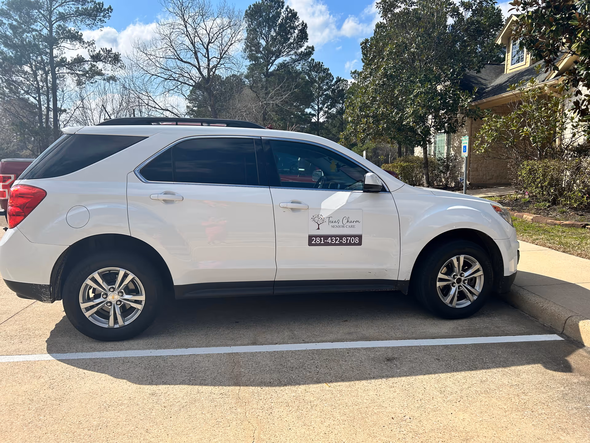 White SUV with Texas Charm Senior Care logo parked in a parking lot beside a building