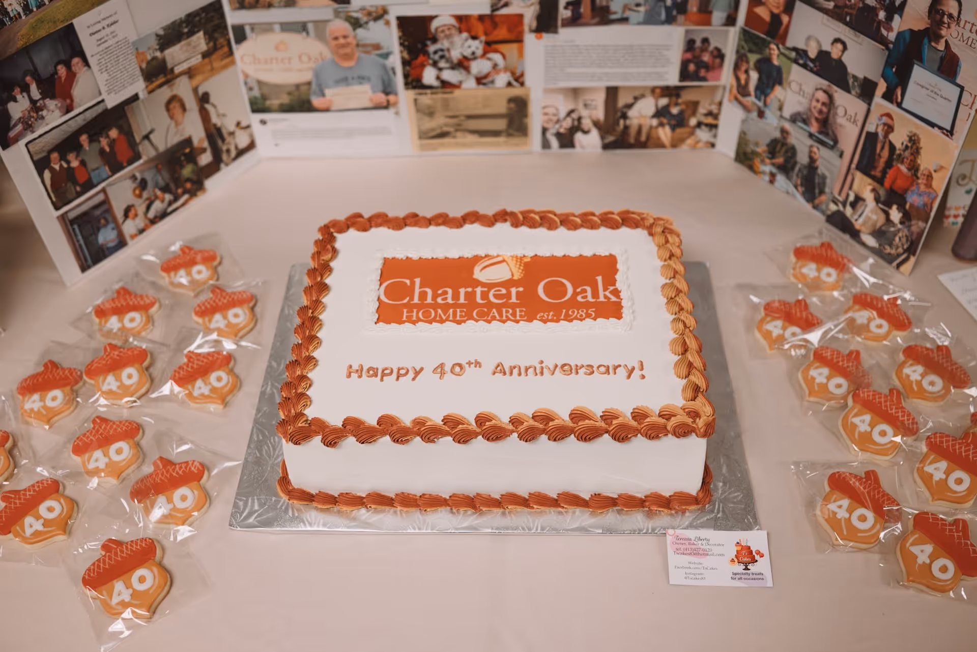 White cake with orange piping and Charter Oak Home Care logo, surrounded by 40th anniversary cookies.