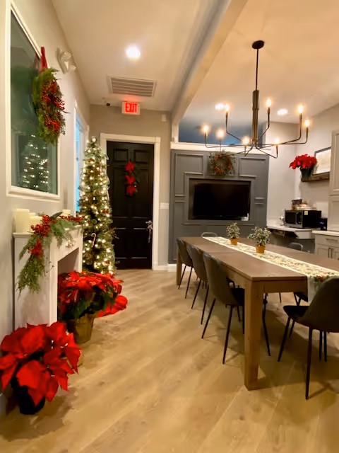 Festive dining room in a senior facility with a long table, Christmas tree, and fireplace.