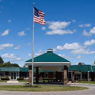 Front view of River Ridge Living Center with flagpole and green entrance canopy.