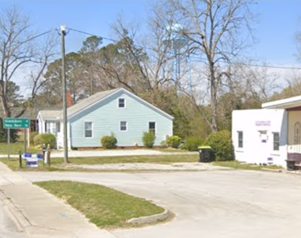 Exterior view of a light-blue, single-story building with a white annex on a street.