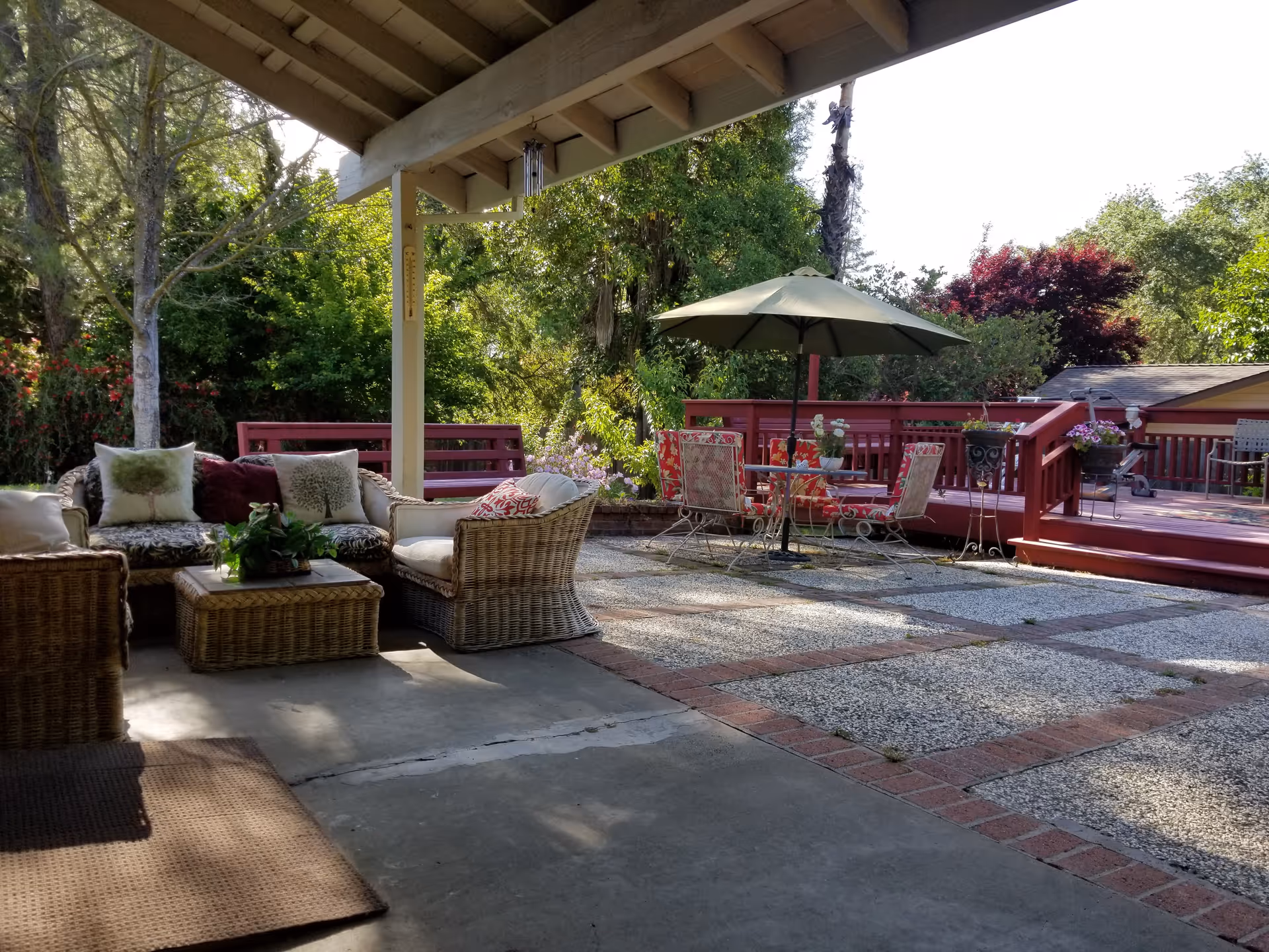 Outdoor patio area with wicker seating, umbrella, and red wooden railing.