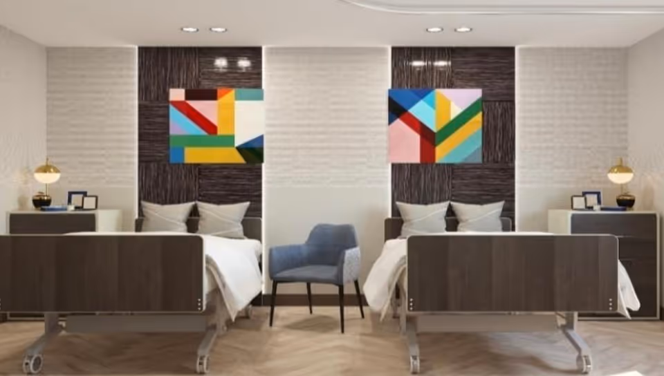 Two hospital beds with a blue chair between them in a modern patient room.
