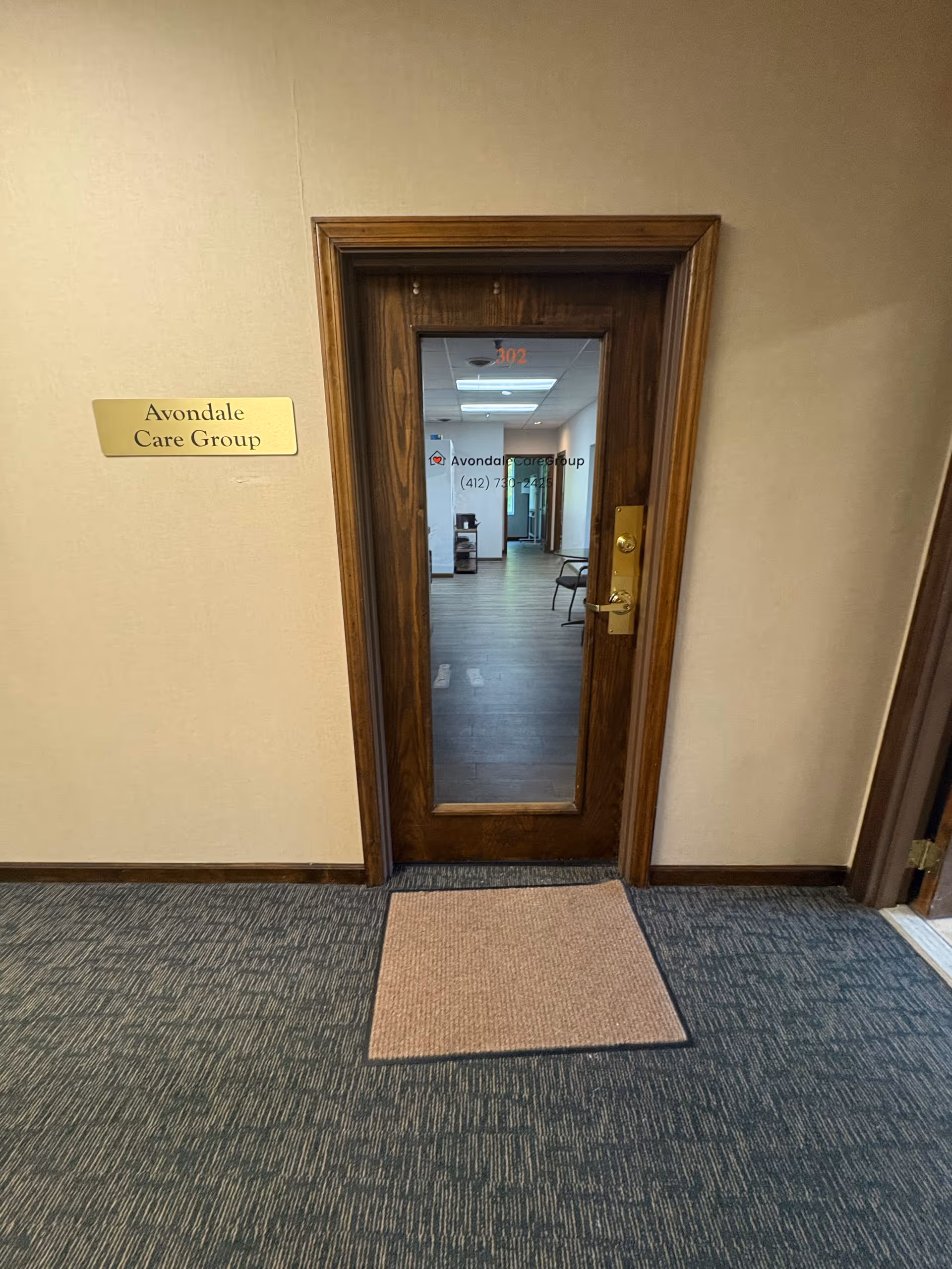 Wood-framed glass door opens into a hallway at Avondale Care Group.
