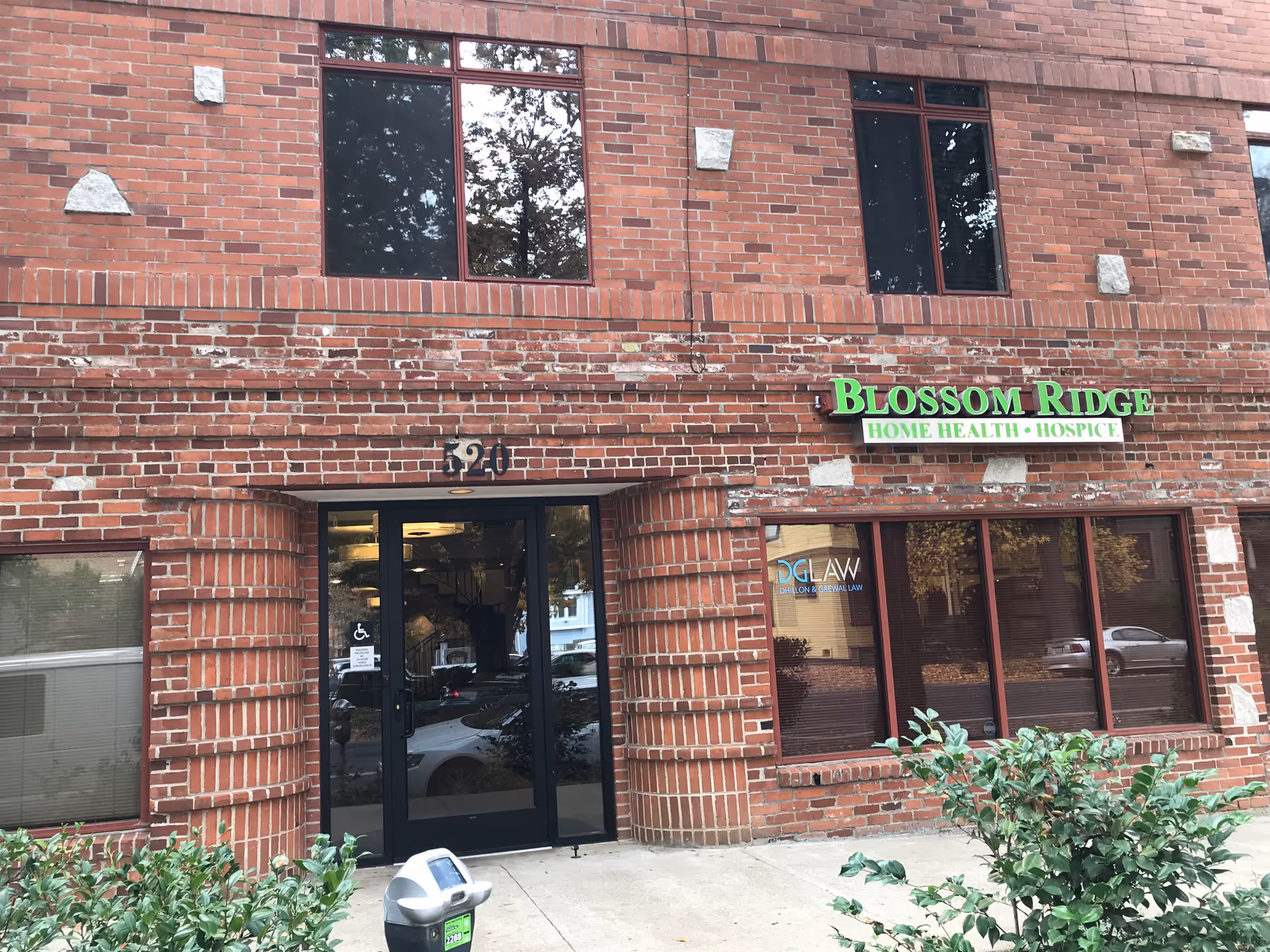 Brick building exterior with Blossom Ridge Home Health Hospice sign and glass entrance door.
