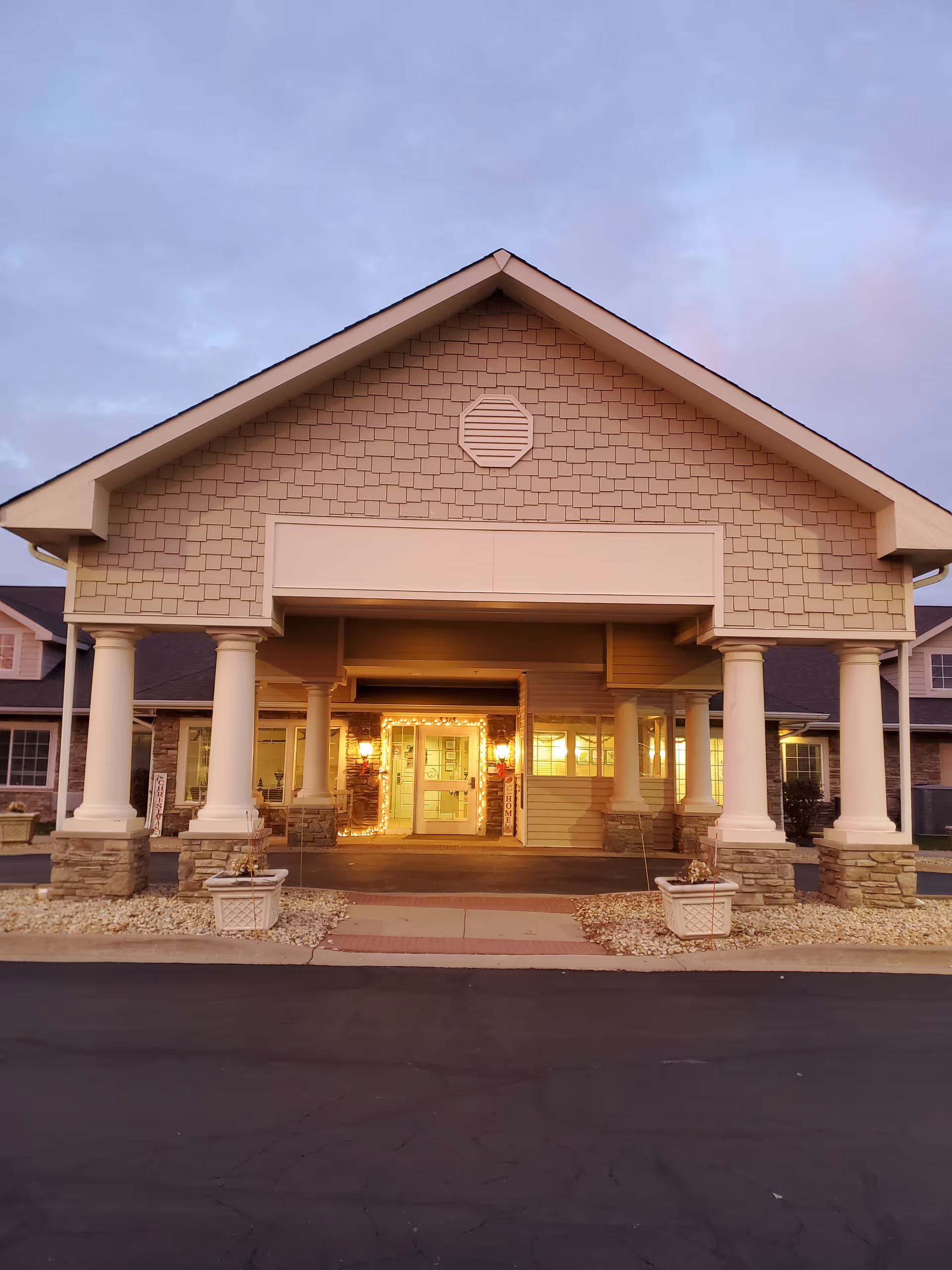 Front entrance of Rock Run Memory Care building with columns and warm lighting.