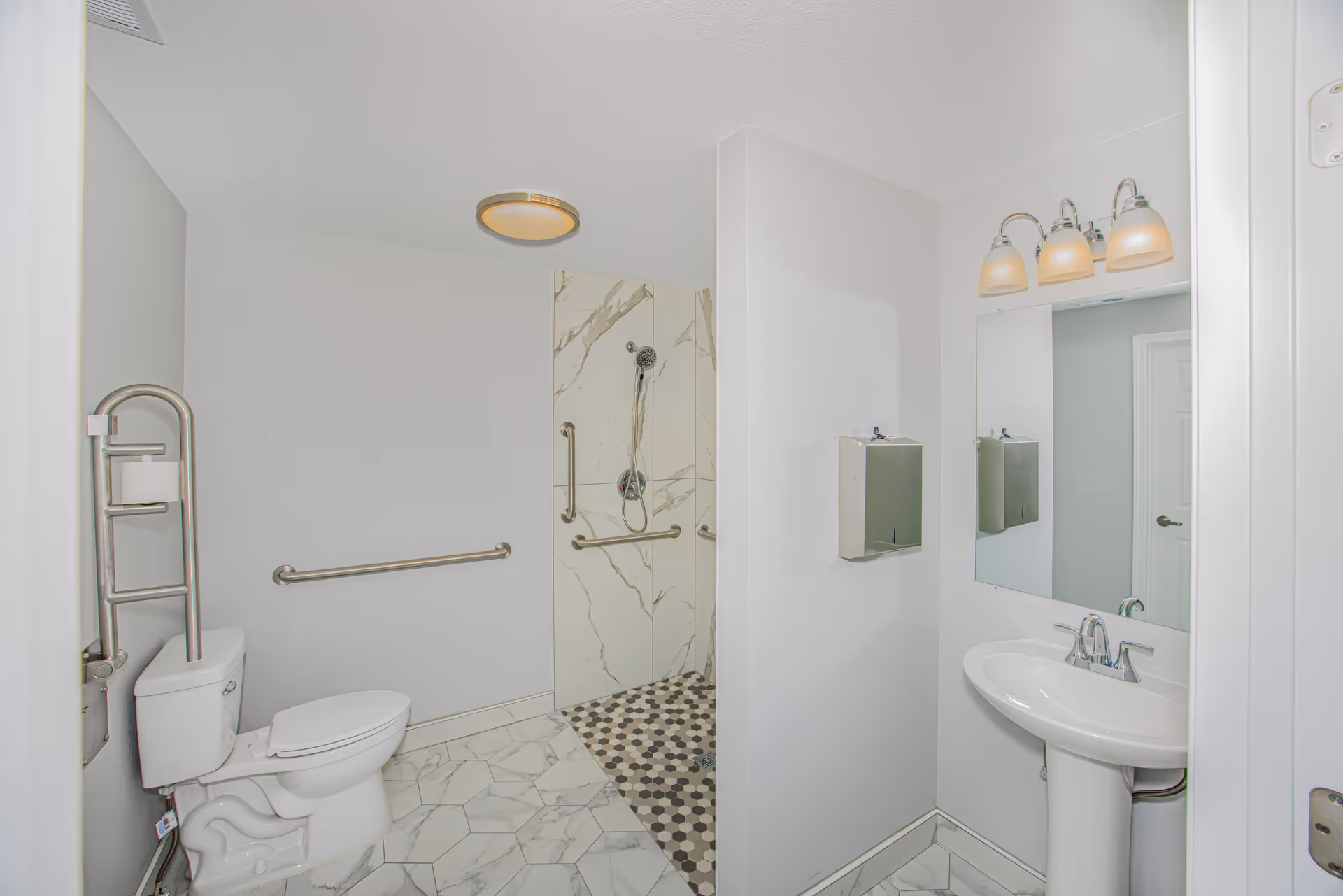 Accessible bathroom with toilet, grab bars, shower, sink, and mirror.