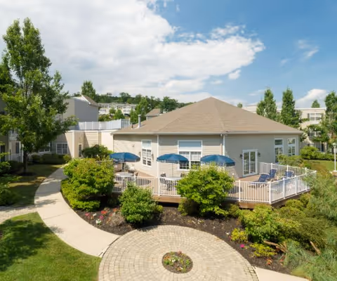 A single-story senior living building with a circular courtyard, deck, and blue umbrellas.