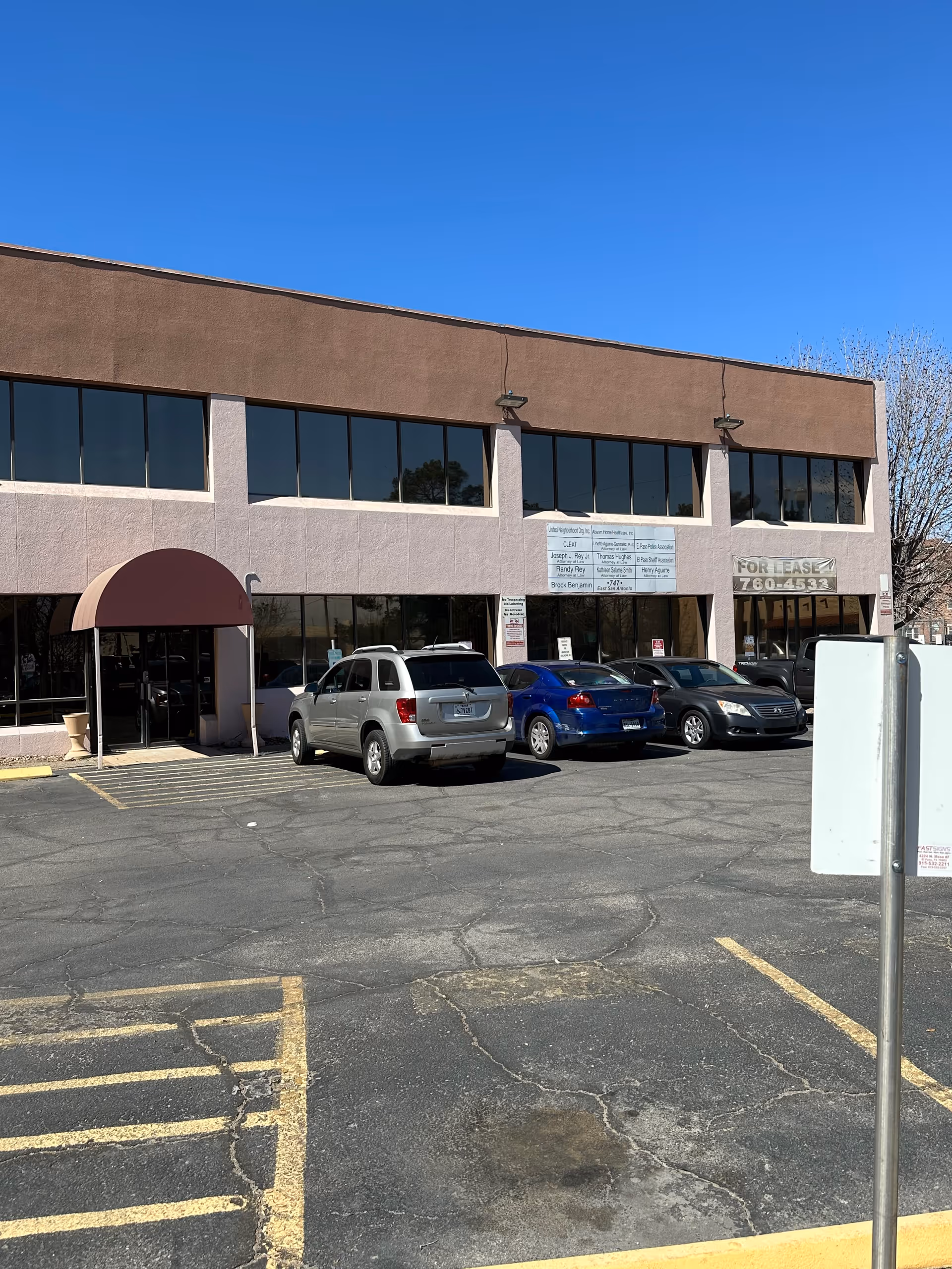 Exterior view of a two-story building with large front windows and parked cars.