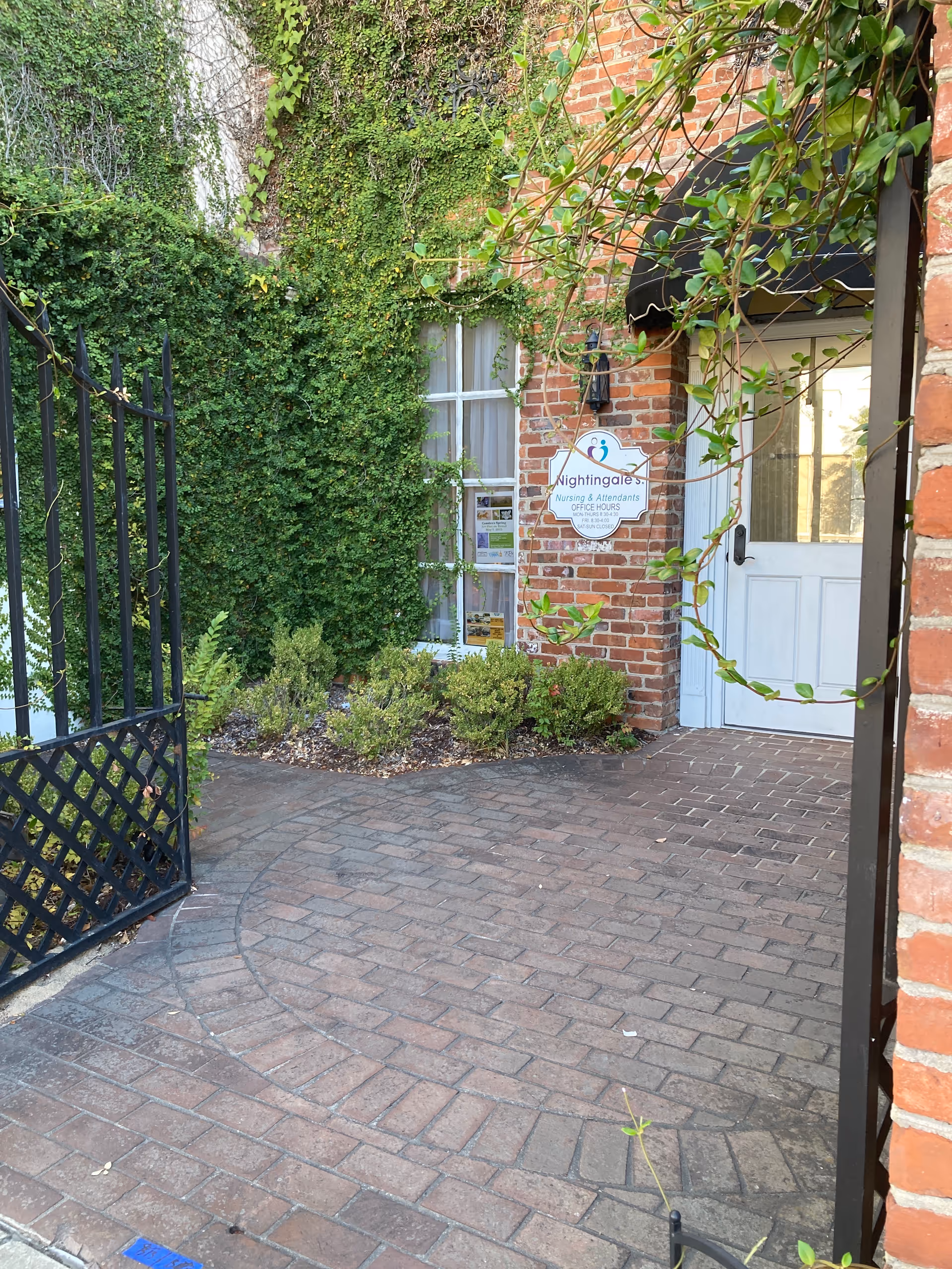 Brick building entrance with ivy, gate, and Nightingale's Nursing & Attendants sign.