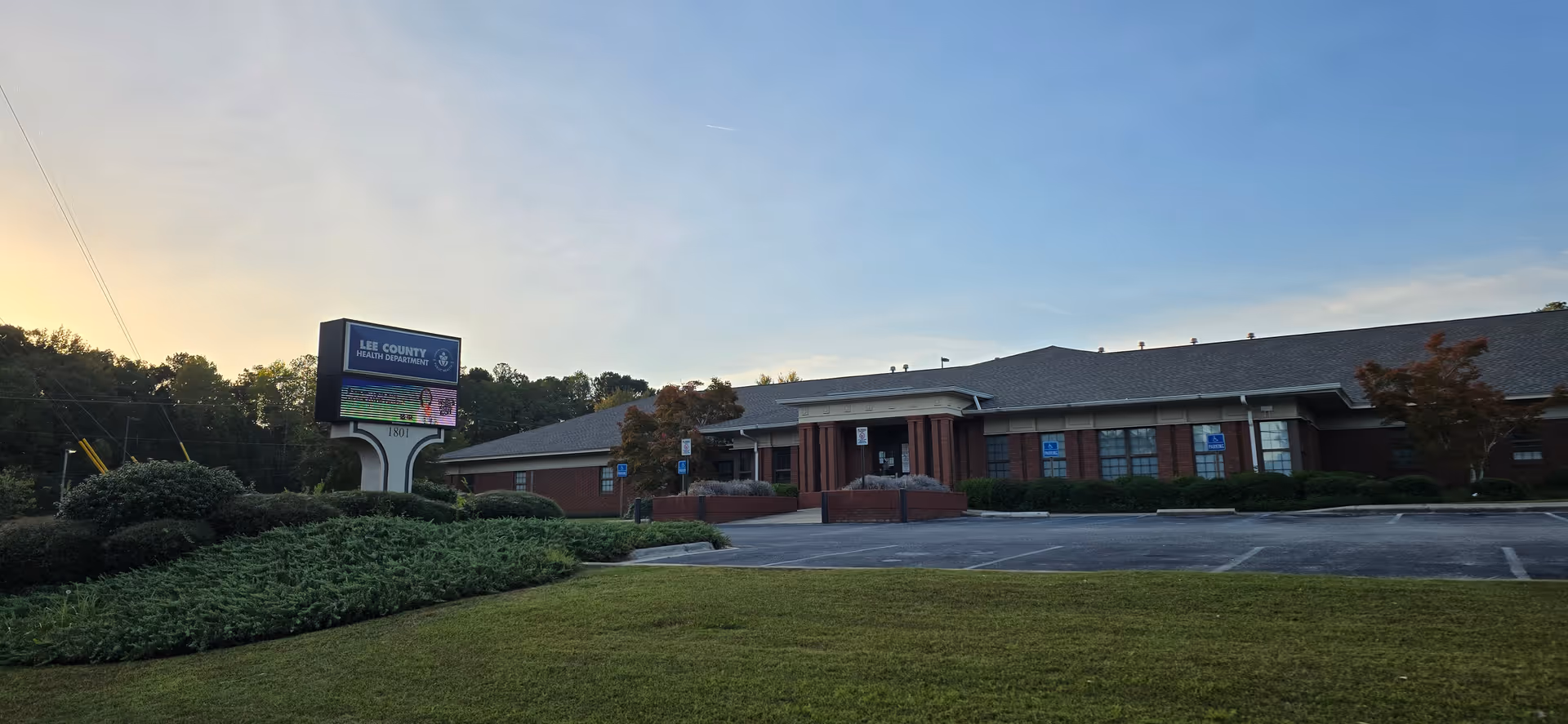 Brick, single-story Lee County Health Department building with sign and parking lot.