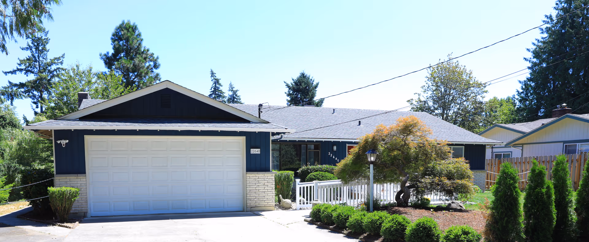Blue single-story house with a two-car garage and landscaped front yard.