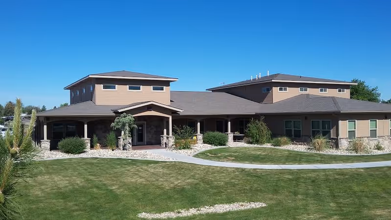 Exterior view of Sunset Estates and Villa, a low, sprawling facility with landscaped lawn and walkway.