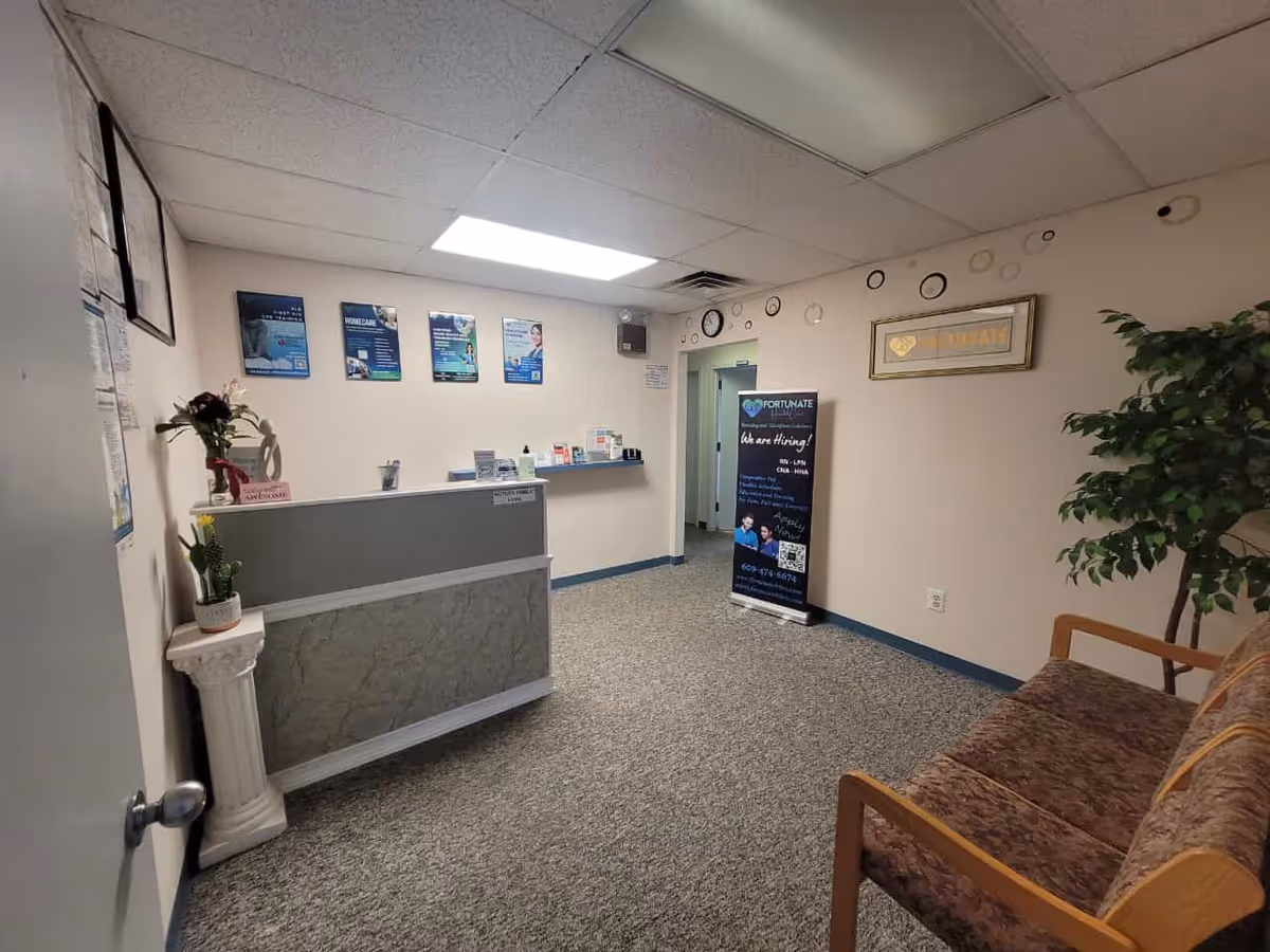 Front desk in a small reception area with posters, a couch, and a potted plant.