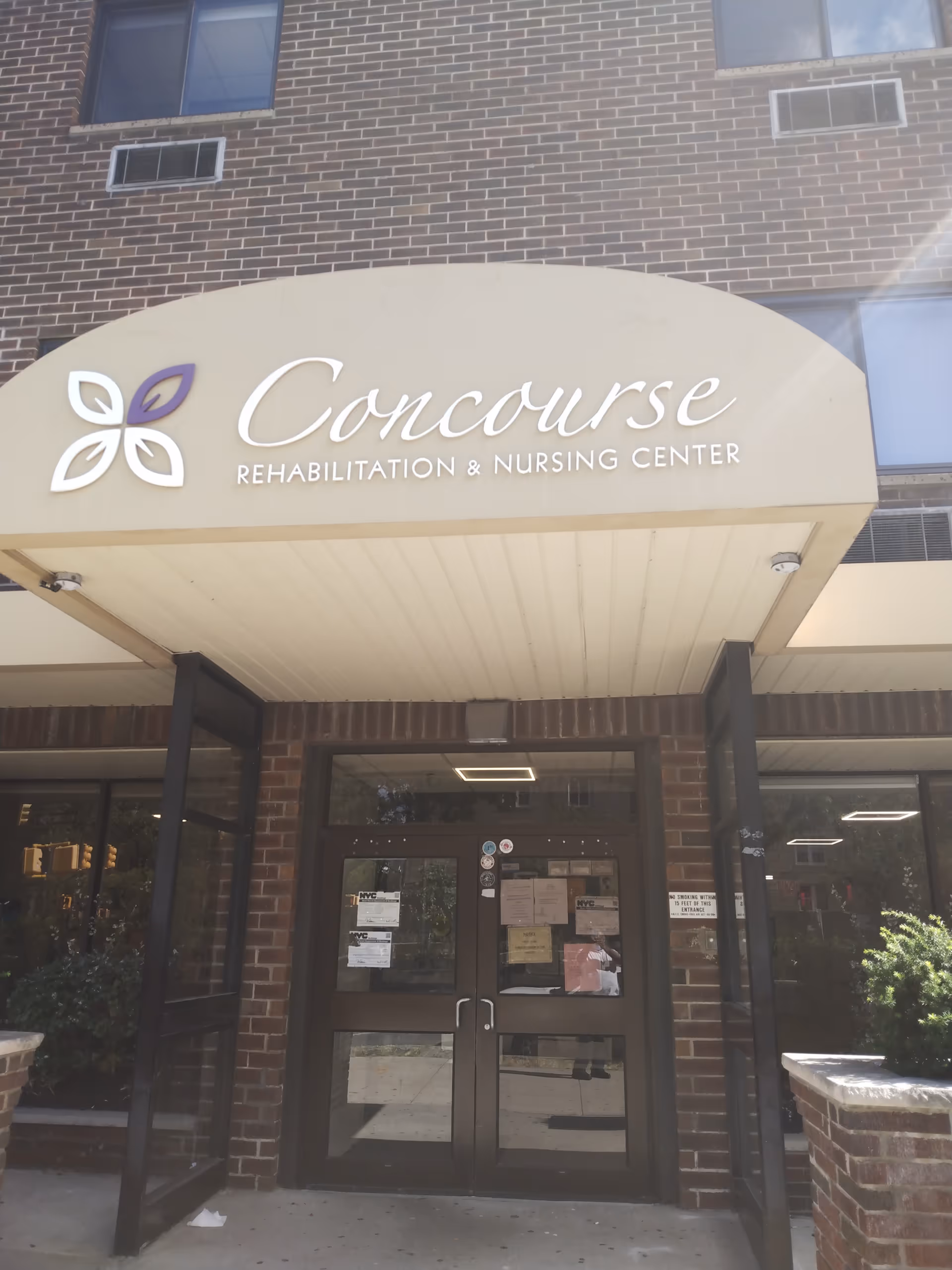 Brick building entrance with curved beige sign reading Concourse Rehabilitation and Nursing Center