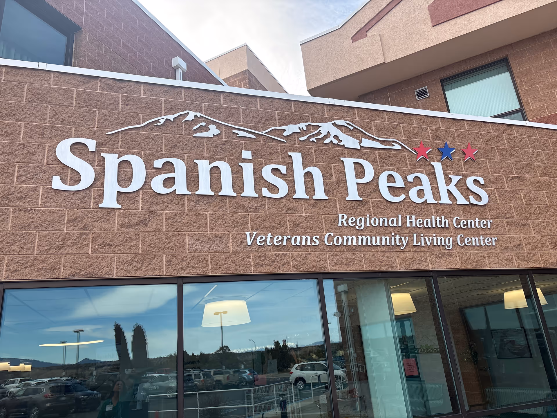 Exterior facade showing the 'Spanish Peaks Regional Health Center Veterans Community Living Center' sign mounted on a brick wall above windows.