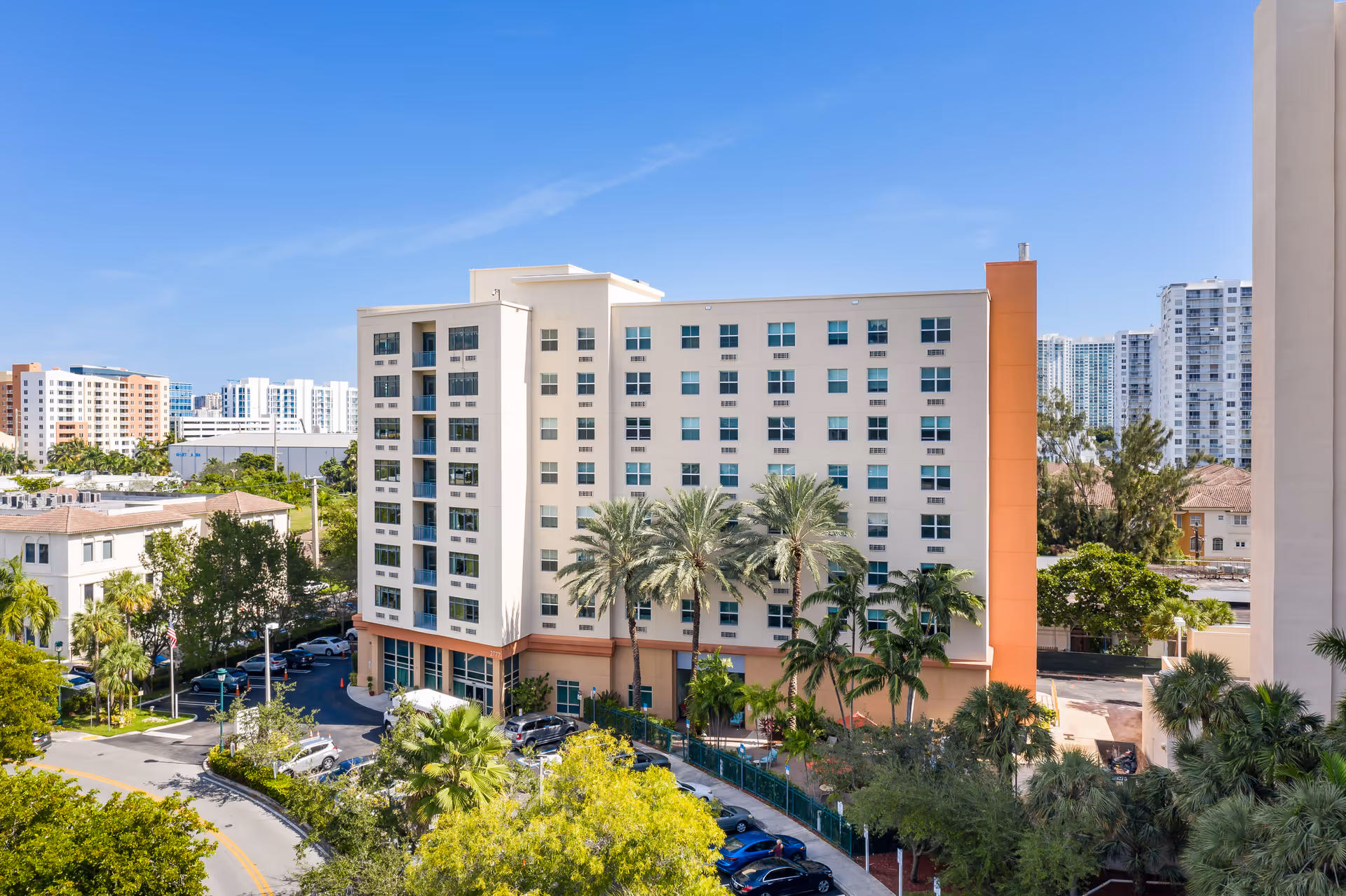 Exterior view of The Sterling Aventura, a multi-story senior living building with palm trees.