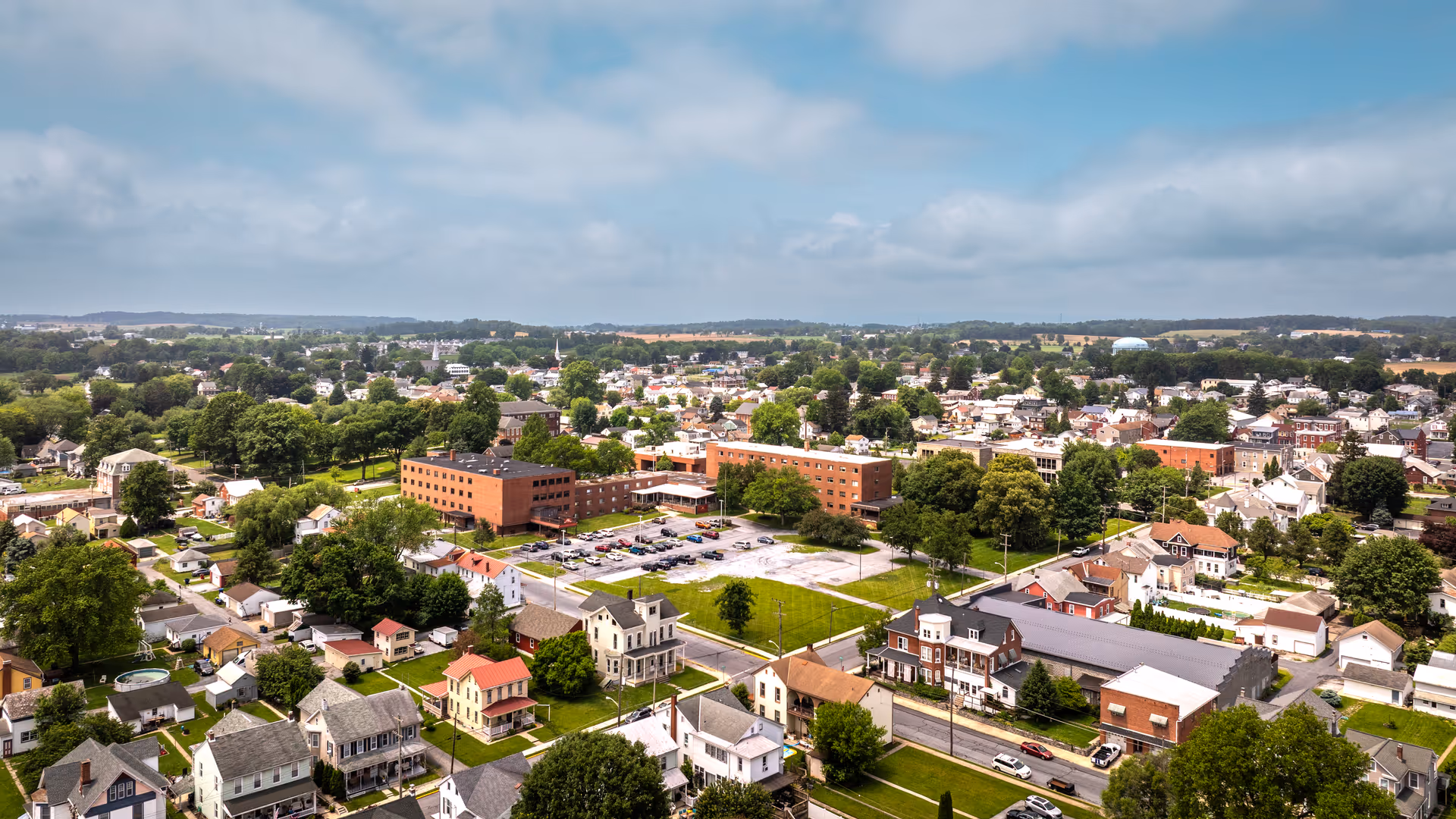 Aerial view of a small town with a prominent brick building and surrounding homes.