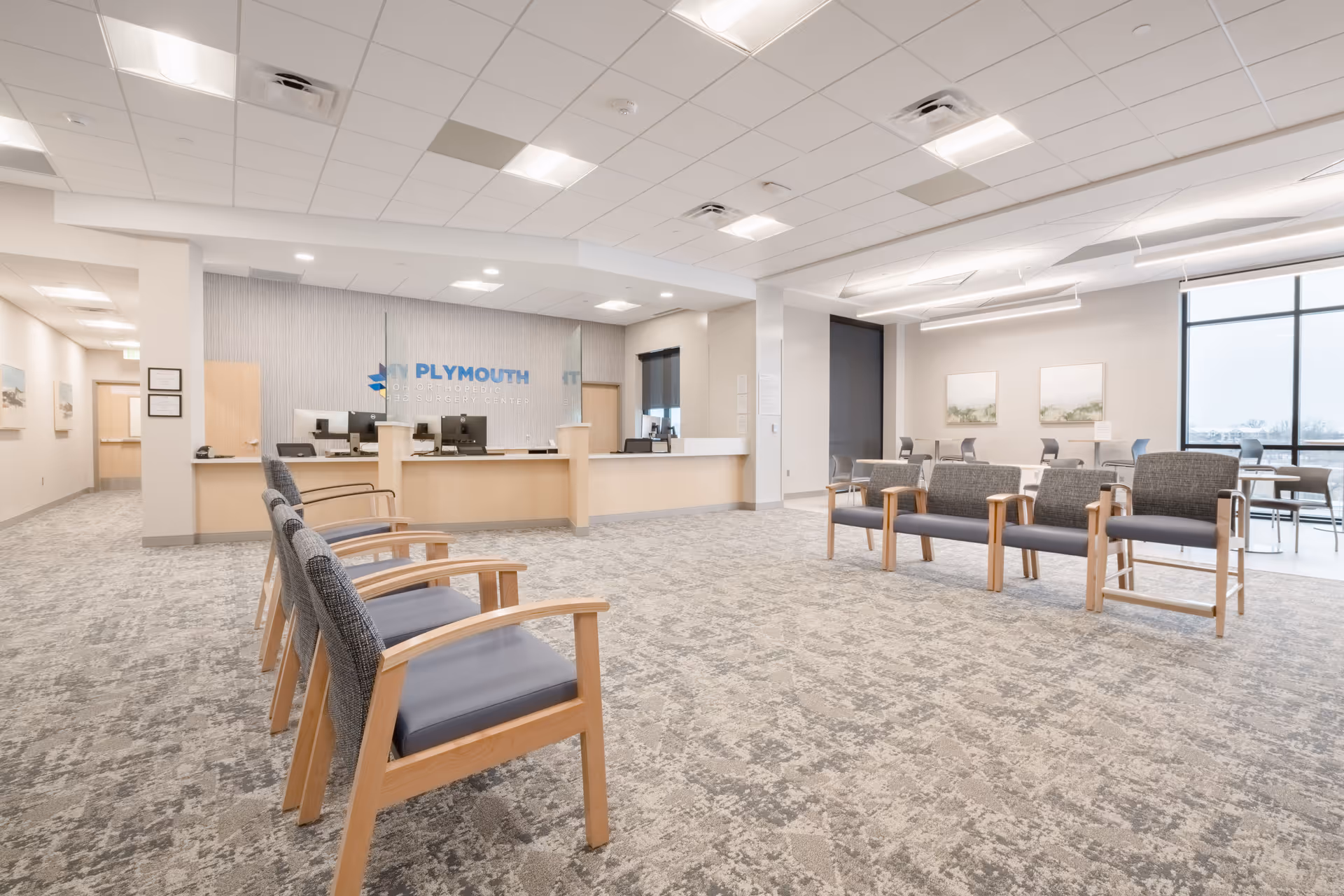 Spacious waiting area with wooden-framed chairs and a front reception desk.