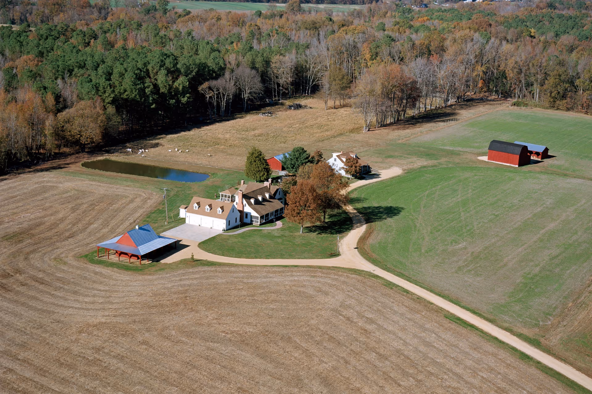 Aerial view of a rural farmstead with a central house and red barns.