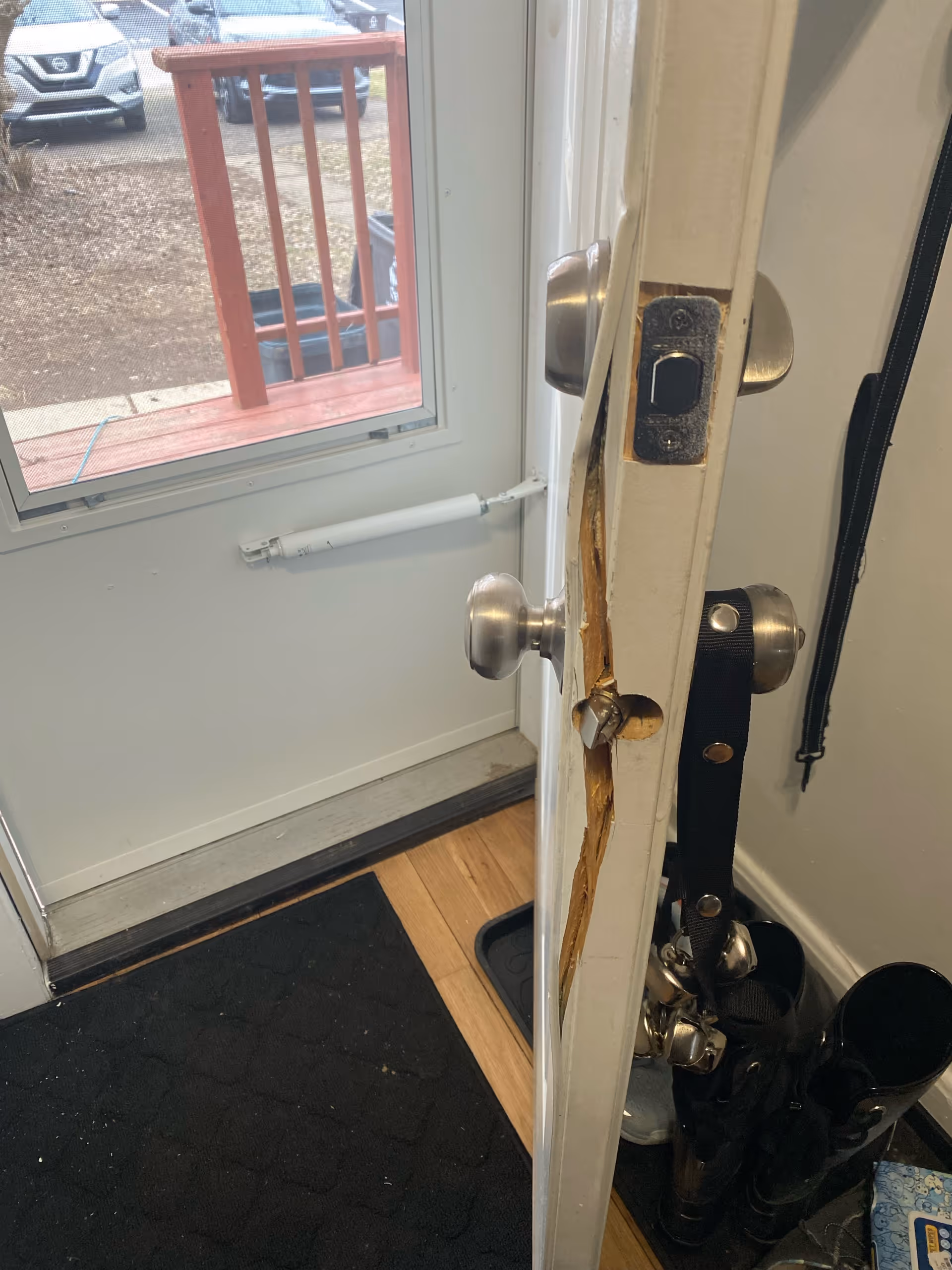 Interior doorway with a damaged door frame, exposed wood, and a view of an outside deck.