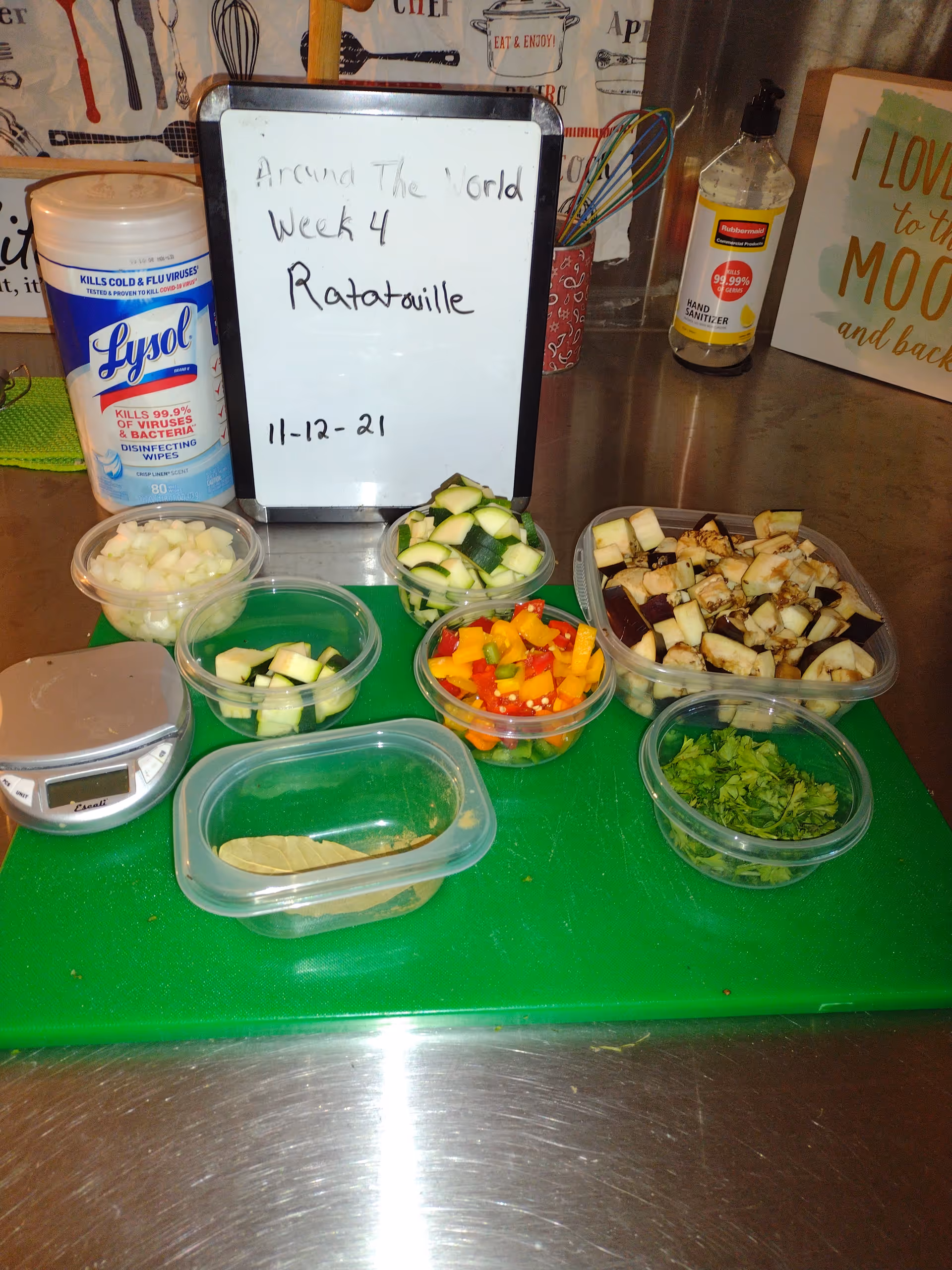 Kitchen counter with chopped vegetables in clear containers and a whiteboard labeled Ratatouille.
